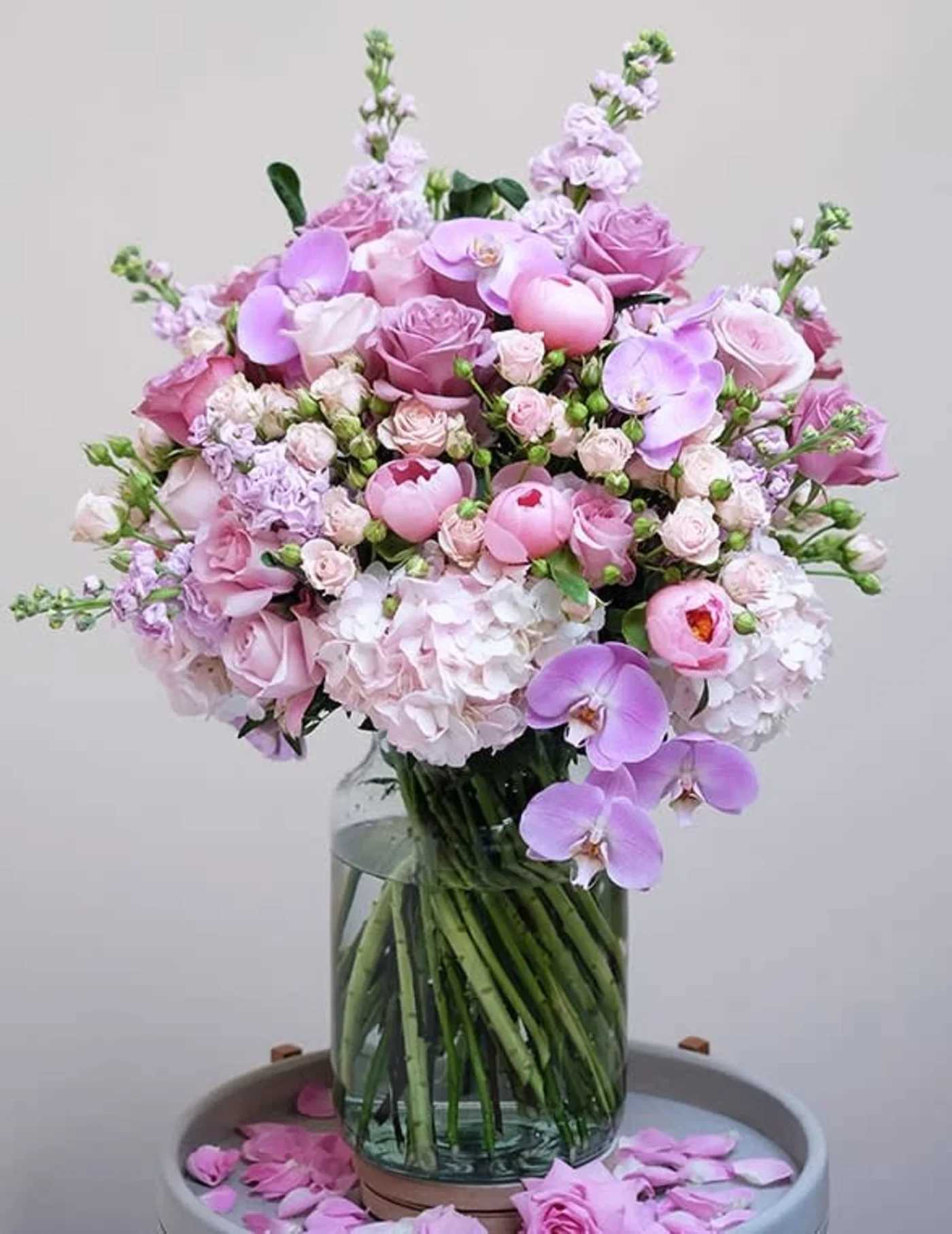 exquisite flower bouquet  - This exquisite flower bouquet in rich shades of pink showcases a captivating ensemble of roses, hydrangeas, peonies, and orchids, thoughtfully selected to create a harmonious blend of colours and textures. Presented in a minimal clear glass vase that adds a touch of modern simplicity, accentuating the grandeur of the floral arrangement. Whether adorning your home, office, or special event, this luxurious bouquet promises to leave a lasting impression.