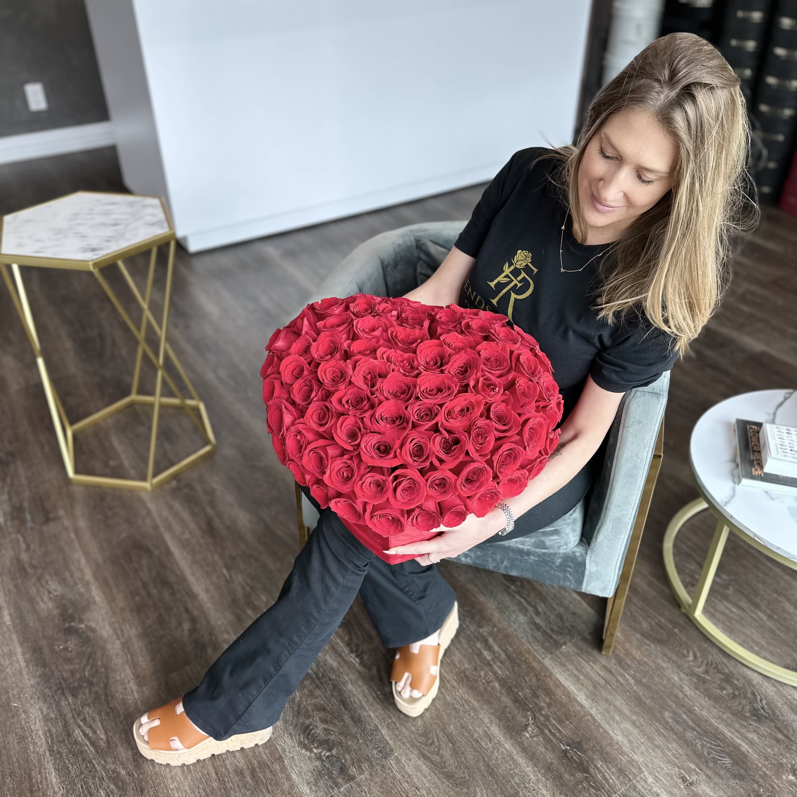 Woman holding a large heart-shaped bouquet of red roses