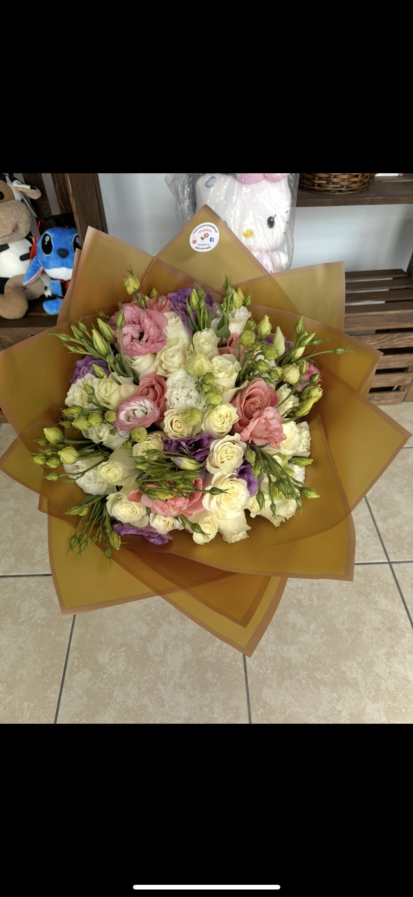 Mixed bouquet of pink, white, and purple flowers wrapped in brown paper