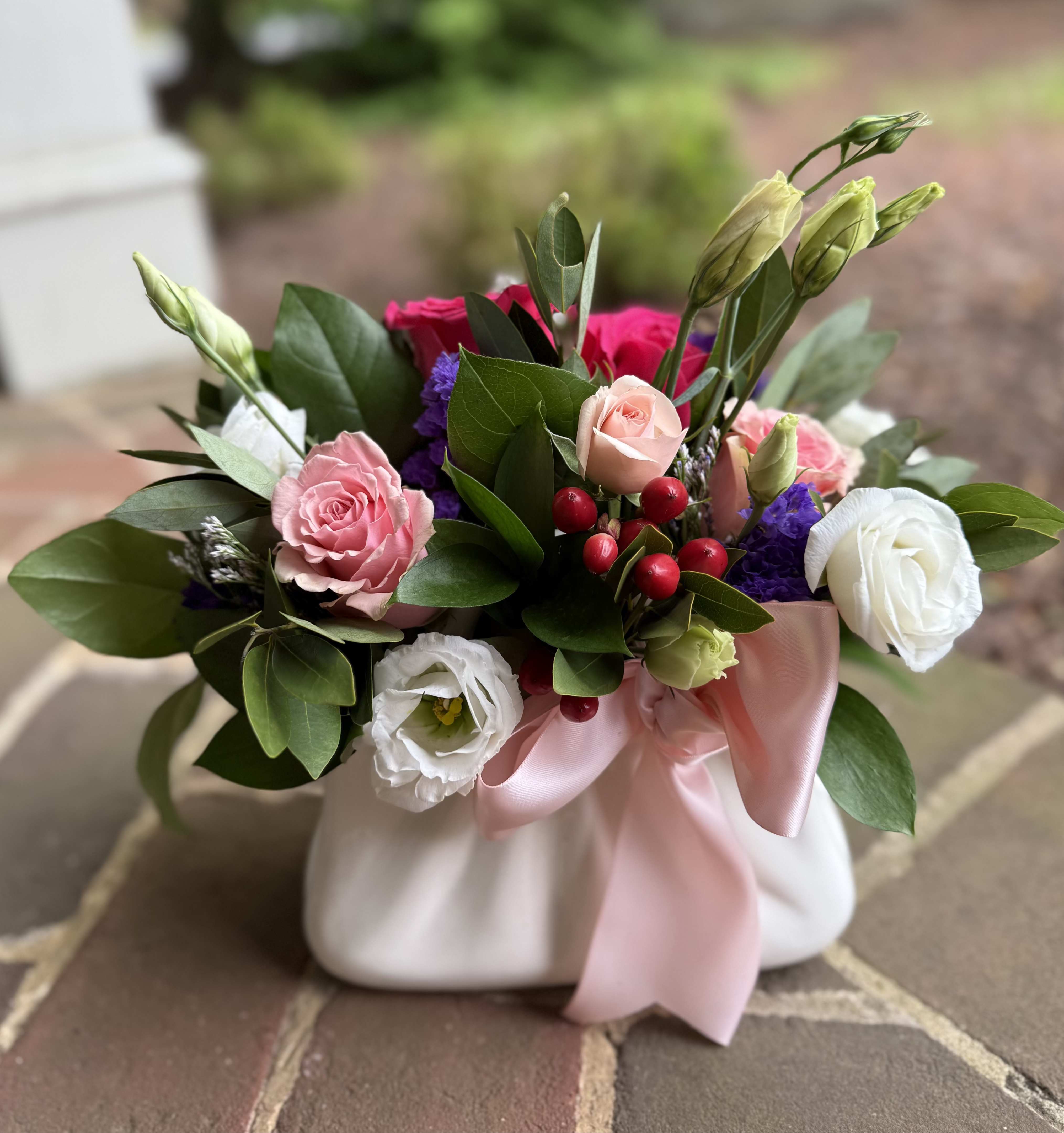 Maison du Mom - Maison du Mom - Wilmington DE, Local Delivery  Playful pinks and soft whites, Maison du Mom is the token of appreciation your mom has been looking for. A white ceramic purse cradles roses, lisianthus, hypericum, and statice that creates the perfect way to say "I love you."   Perfect for birthdays, congratulations, get well wishes or just because, this cheerful bouquet adds a pop of color and a touch of luxury. Handcrafted by your trusted Wilmington florist, each arrangement is made fresh to order using premium seasonal flowers.  Why Choose Us? Hand-delivered by a Wilmington Florist Fast, reliable flower delivery in Wilmington, DE High-end blooms, expertly arranged with care.  Order now and brighten someone's day with Maison du Mom - a standout floral gift from your go-to Wilmington, Delaware flower shop. 