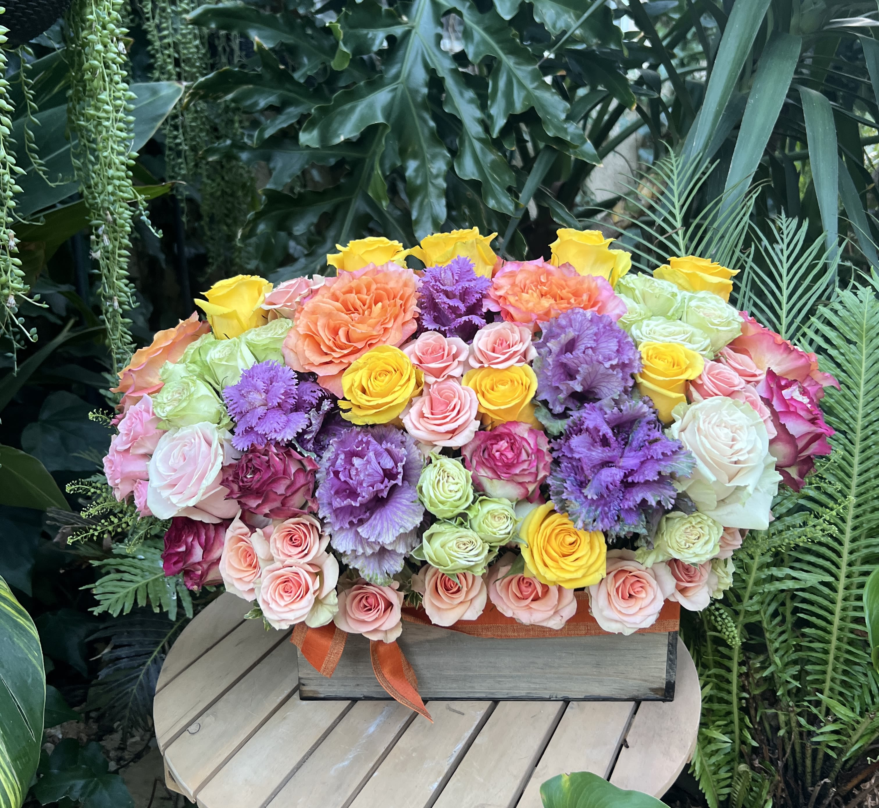 Mixed bouquet of roses and purple ornamental blooms in a wooden box