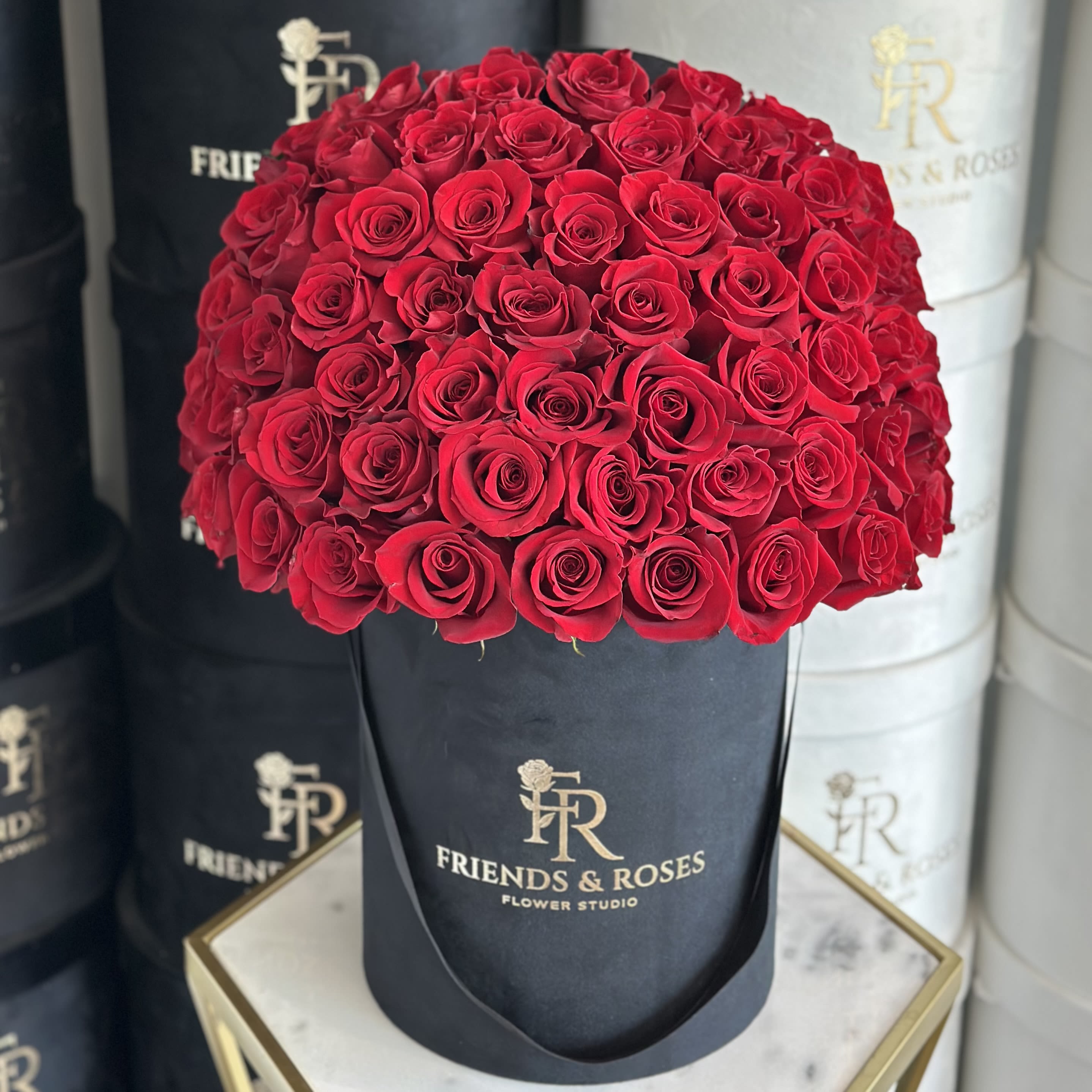 Round bouquet of red roses in a black hatbox