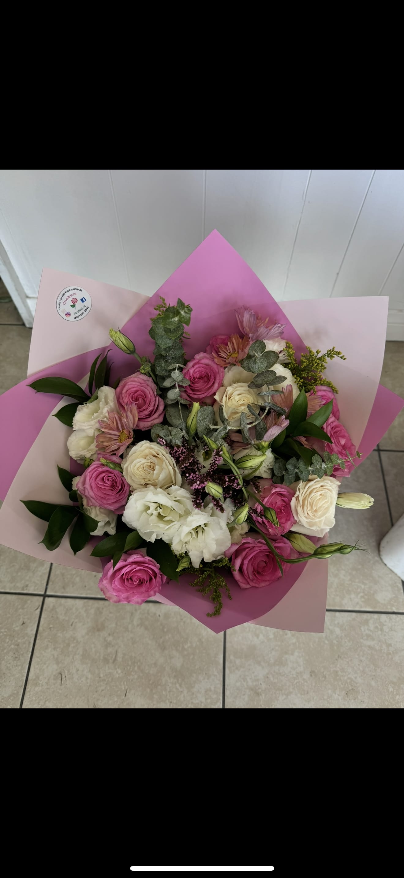 Bouquet of pink and white roses with pale blooms wrapped in pink paper
