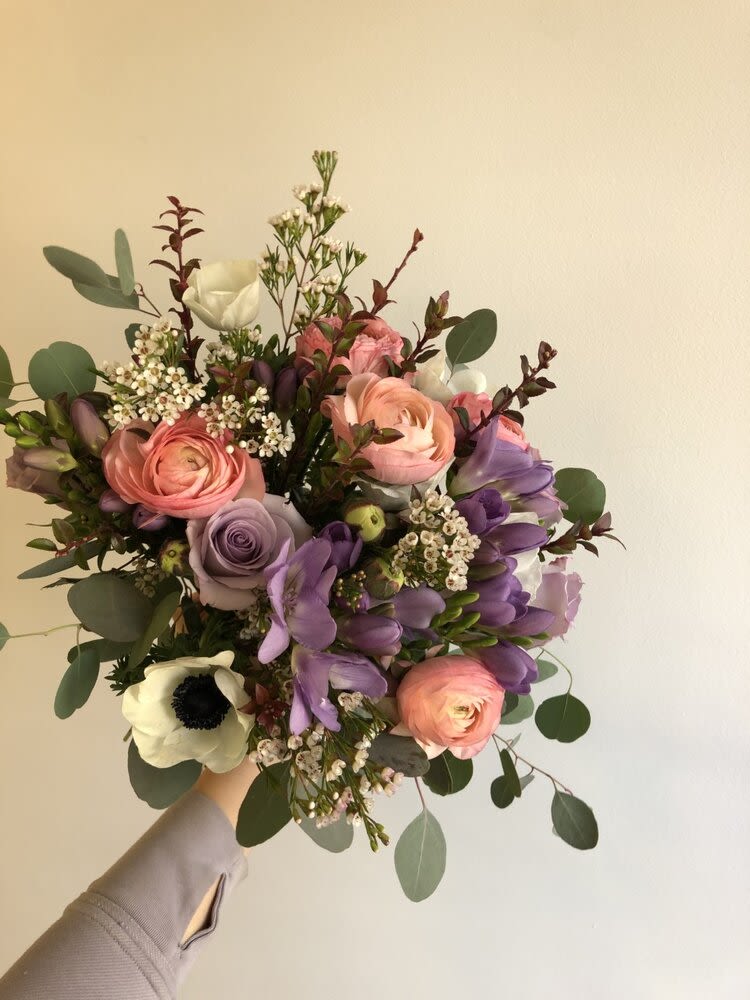 Handheld bouquet of pink, purple, and white flowers with eucalyptus