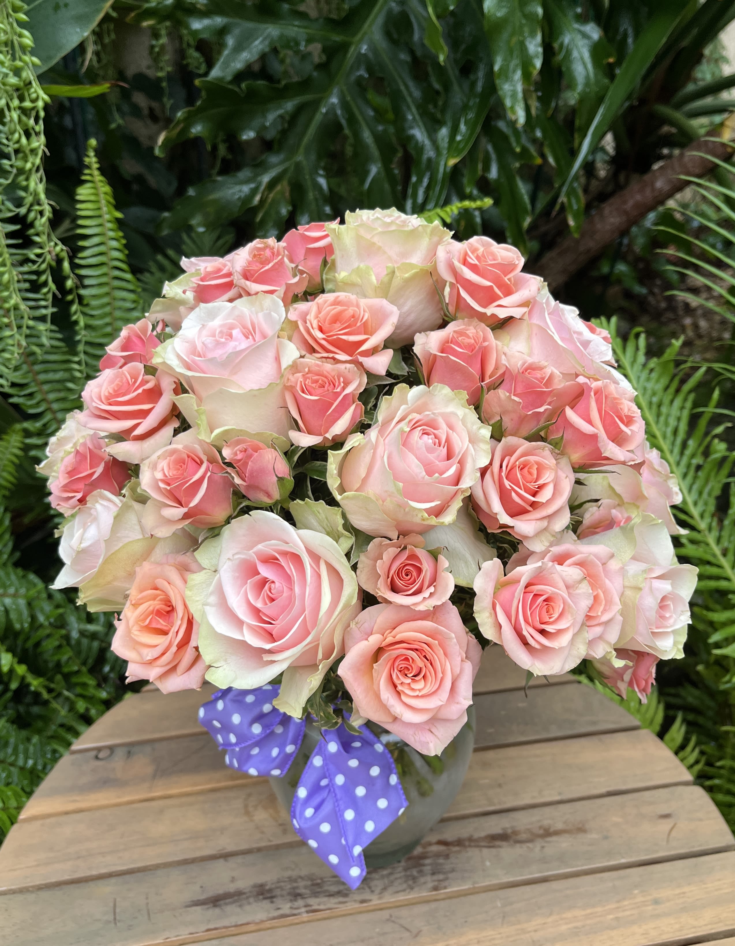 Bouquet of pink roses in a vase with a purple polka-dot ribbon