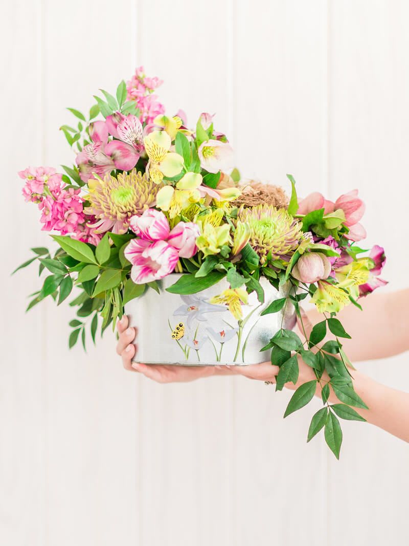 Pink and yellow mixed bouquet in a decorative tin container