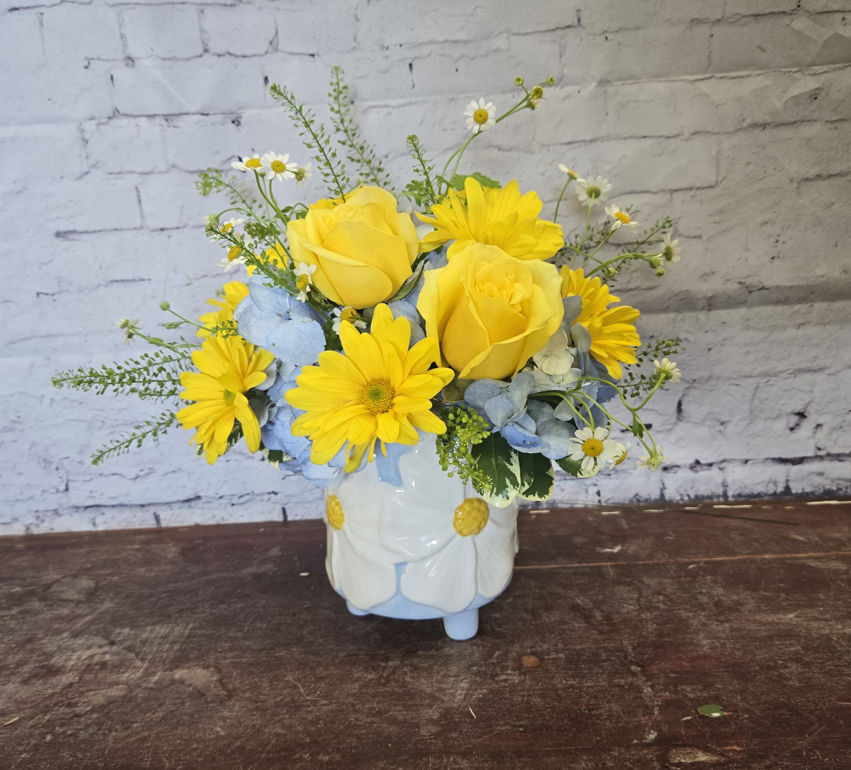 Lemon Drop Delight  - Sun-warm yellow roses and cheerful daisies create an immediate lift-the kind of birthday bouquet or springtime surprise that makes the person you're thinking of smile. This flower arrangement for casual gifting or seasonal display blends sunny yellow, soft blue, crisp white, and fresh green to feel both lively and gently elegant. 