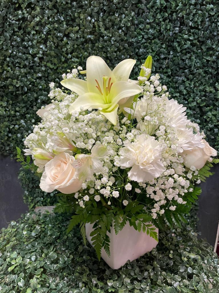 White lily and pale blooms in a white vase