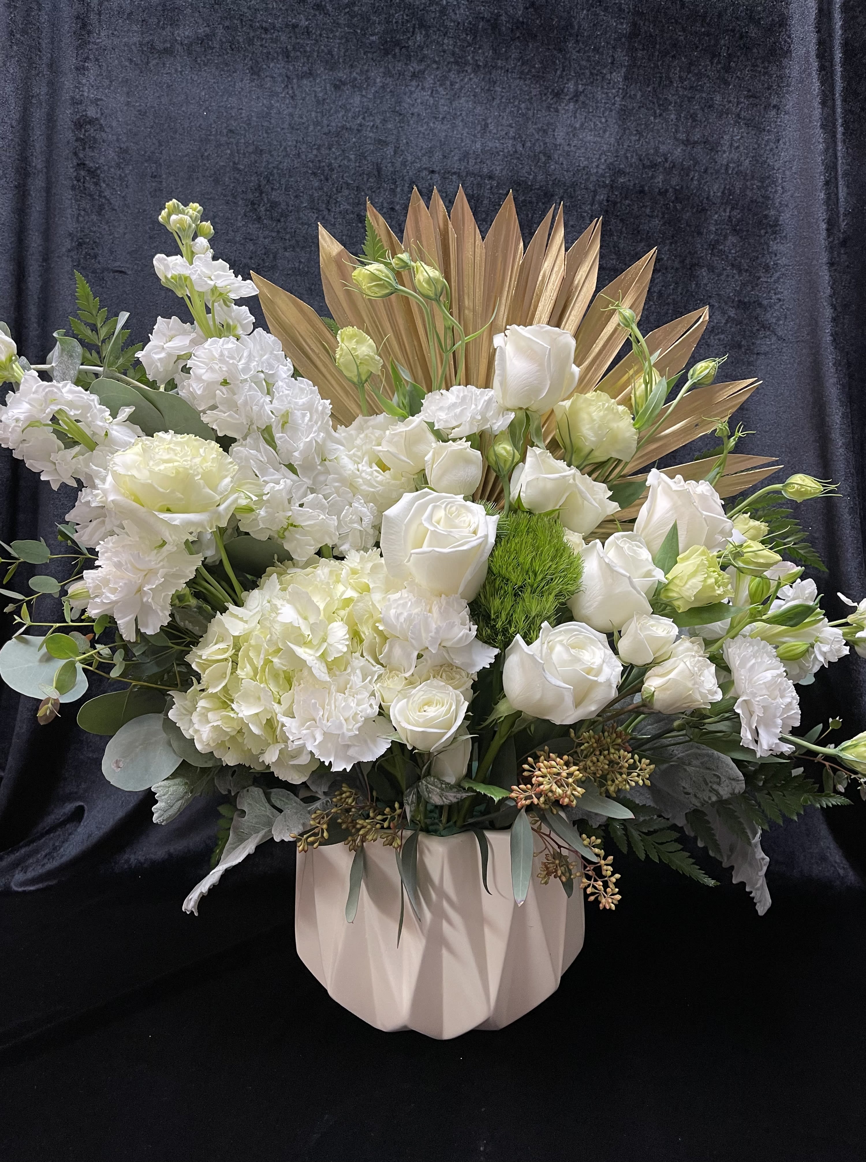 White roses and hydrangeas in a blush vase with gold fan accents