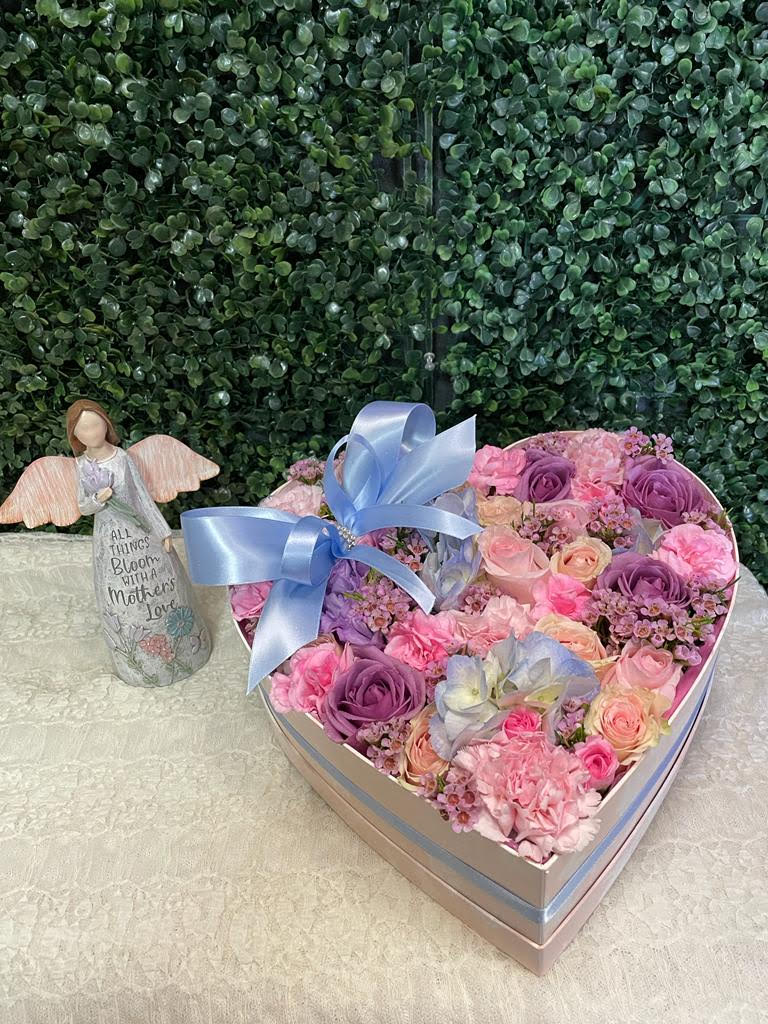 Heart-shaped box of pink and purple roses with a blue ribbon