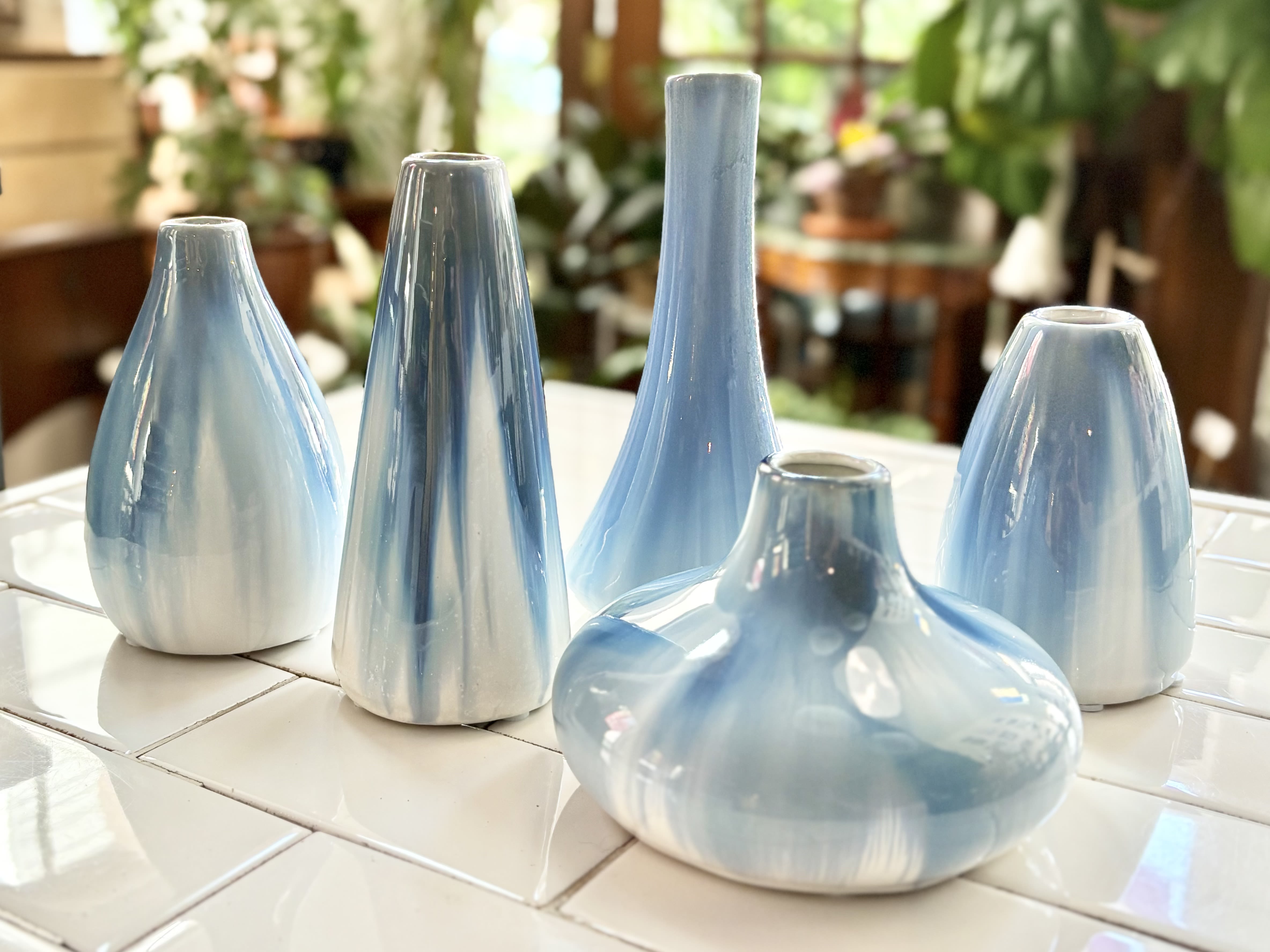 Five light blue ceramic vases on a tiled surface