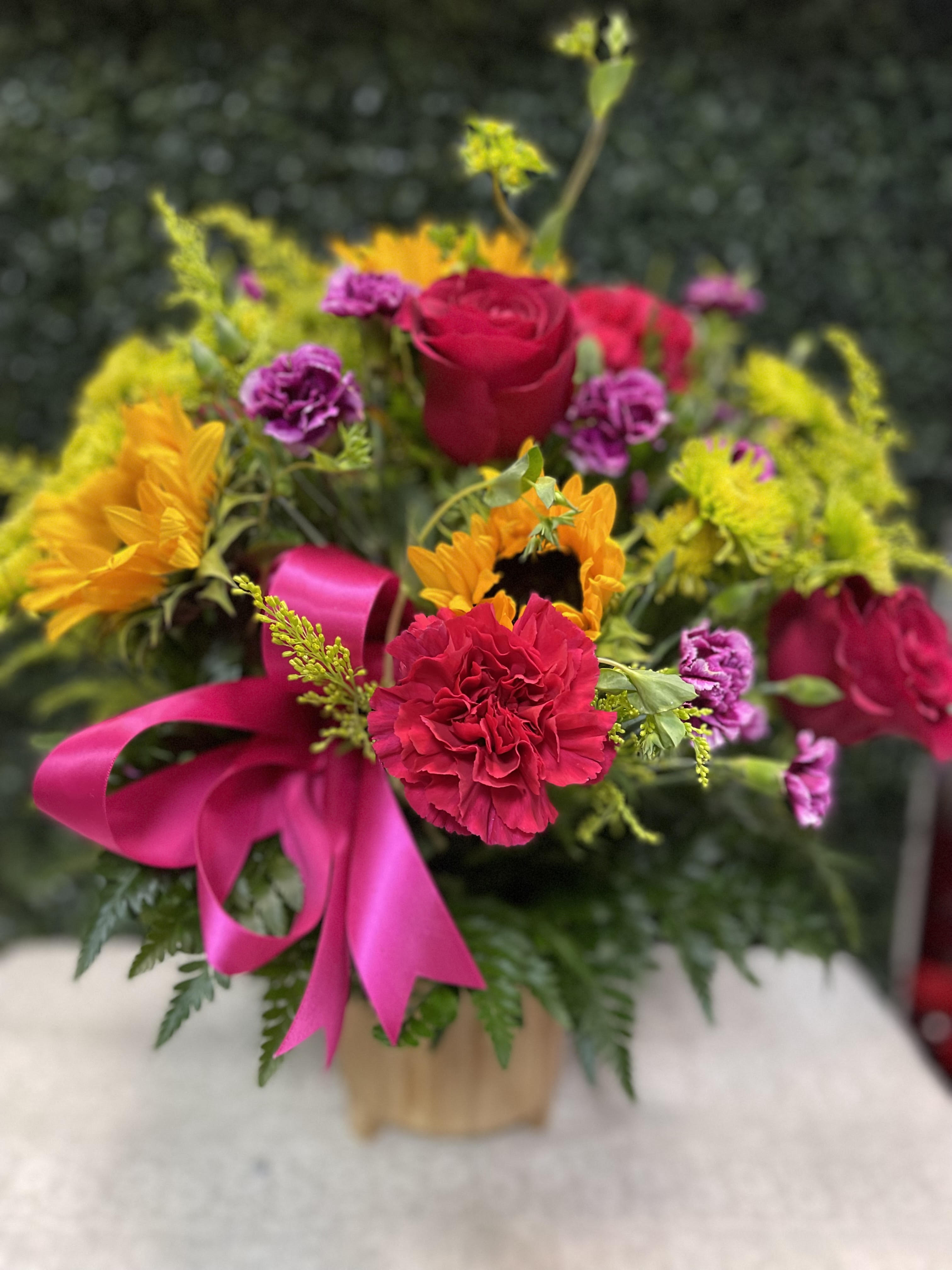 Bright mixed bouquet with roses, sunflowers, and carnations in a vase