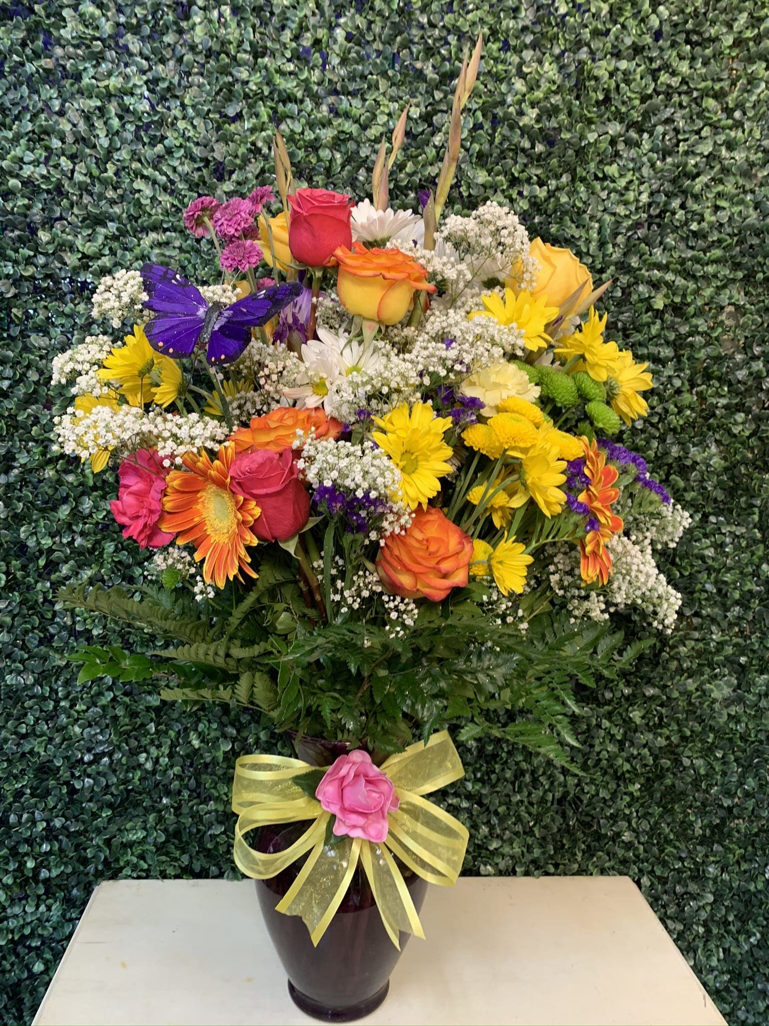 Mixed bouquet in a dark vase with a yellow ribbon