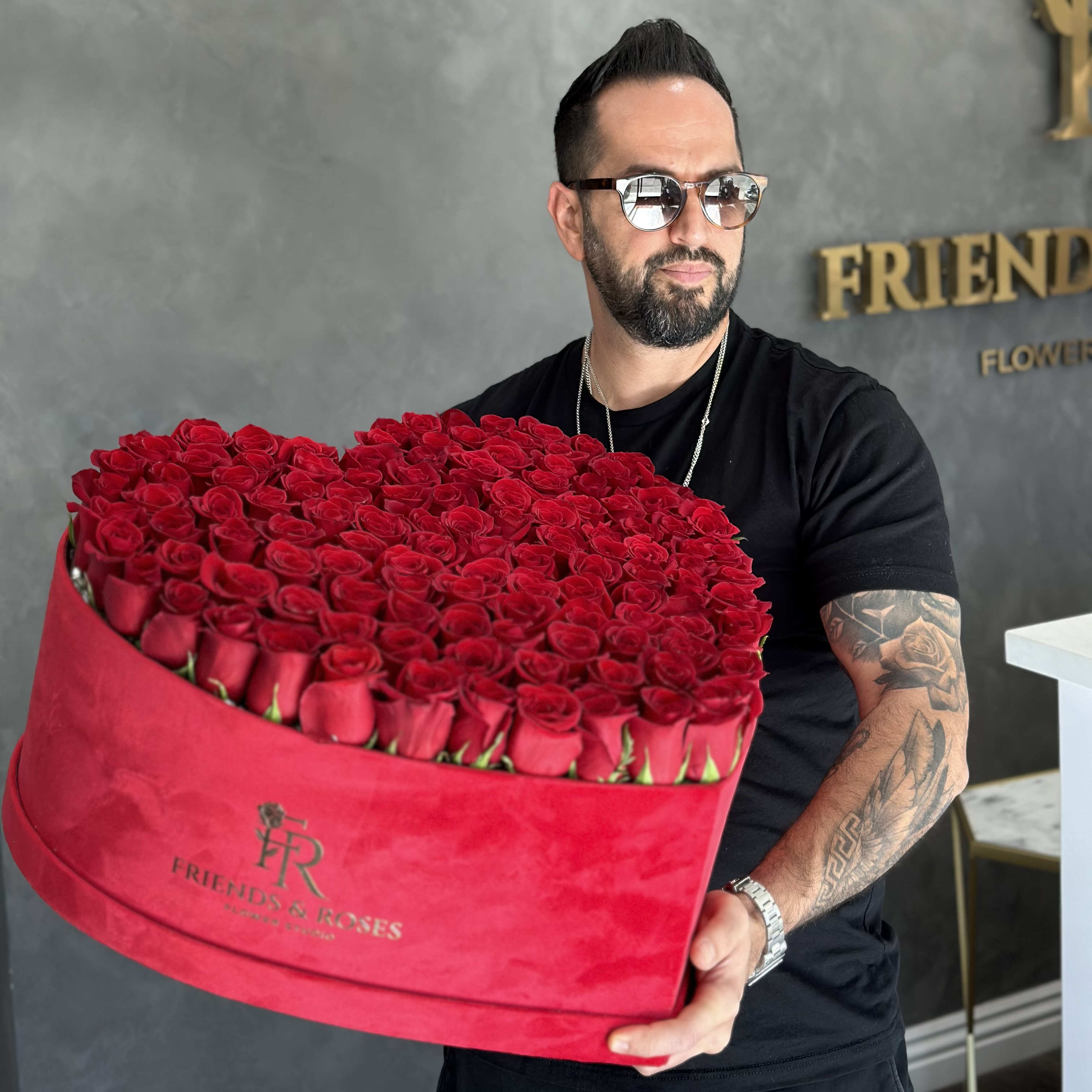 Man holding a large heart-shaped box of red roses