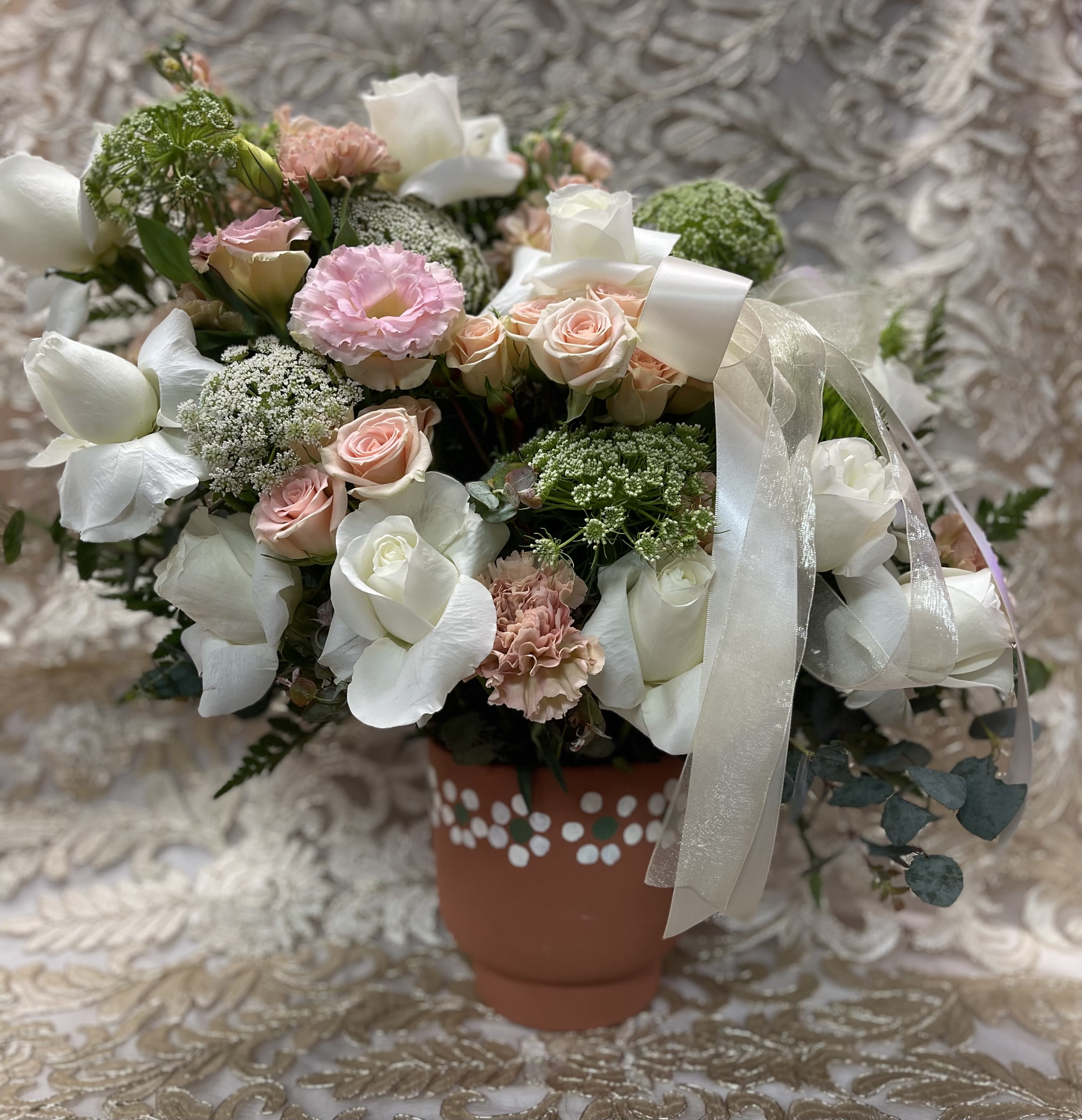 Bouquet of white and blush flowers in a decorated terracotta pot