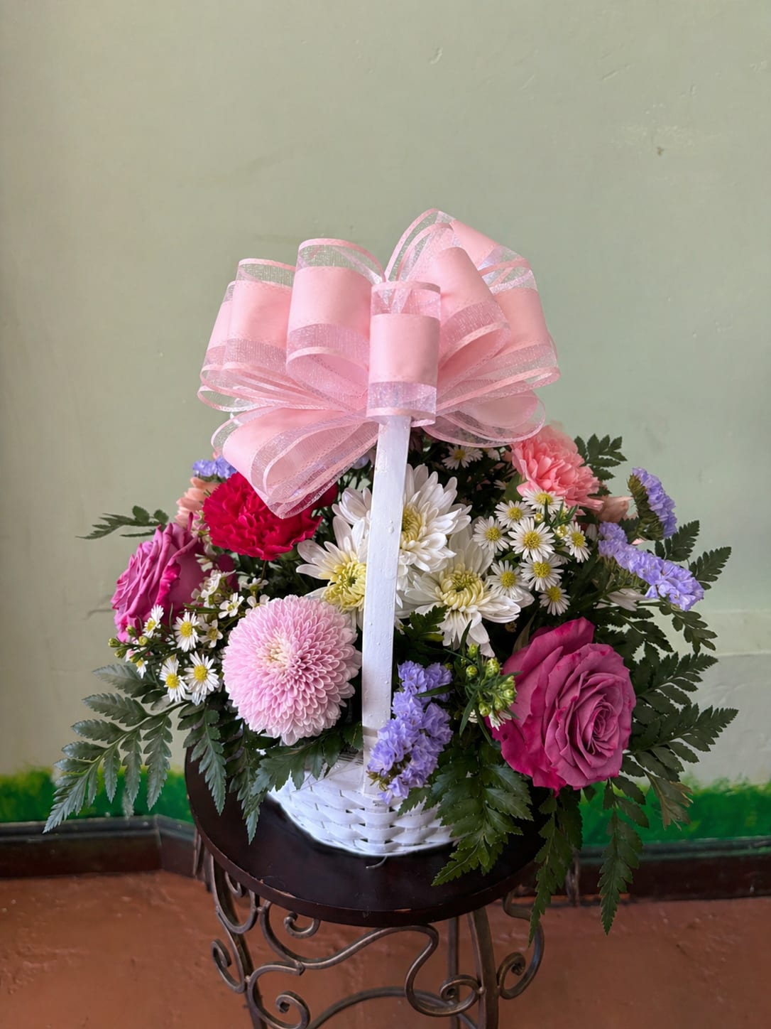 Garden Mix Basket - A charming basket arrangement featuring a mix of flowers and colors designed to create a bright and balanced look. Each piece is handcrafted with seasonal blooms and fresh greenery, making every arrangement unique. The overall style and color palette will be similar, but it may not look exactly like the picture.