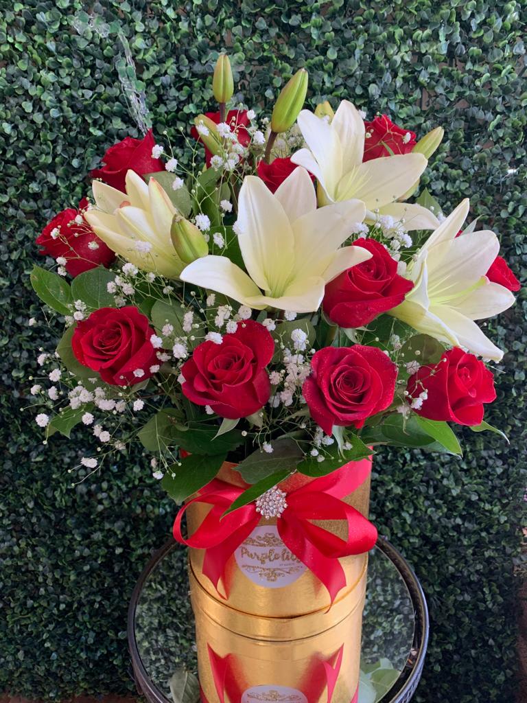 Bouquet of red roses and white lilies in a gold box with a red ribbon