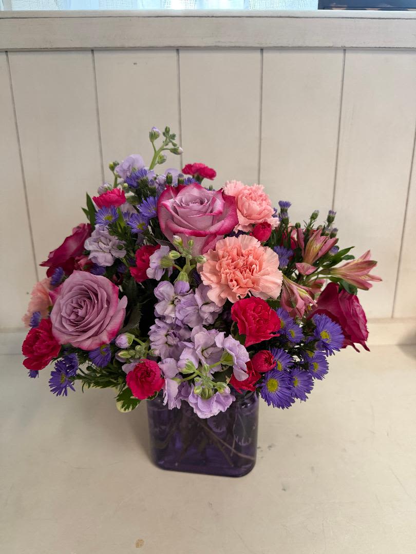 Love You Mom - Red roses, carnations, stock, wax flowers, alstroemeria and misc. fillers in a white cement pot.