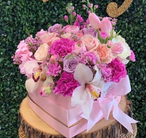 Pink and lavender floral arrangement in a pink box with a ribbon