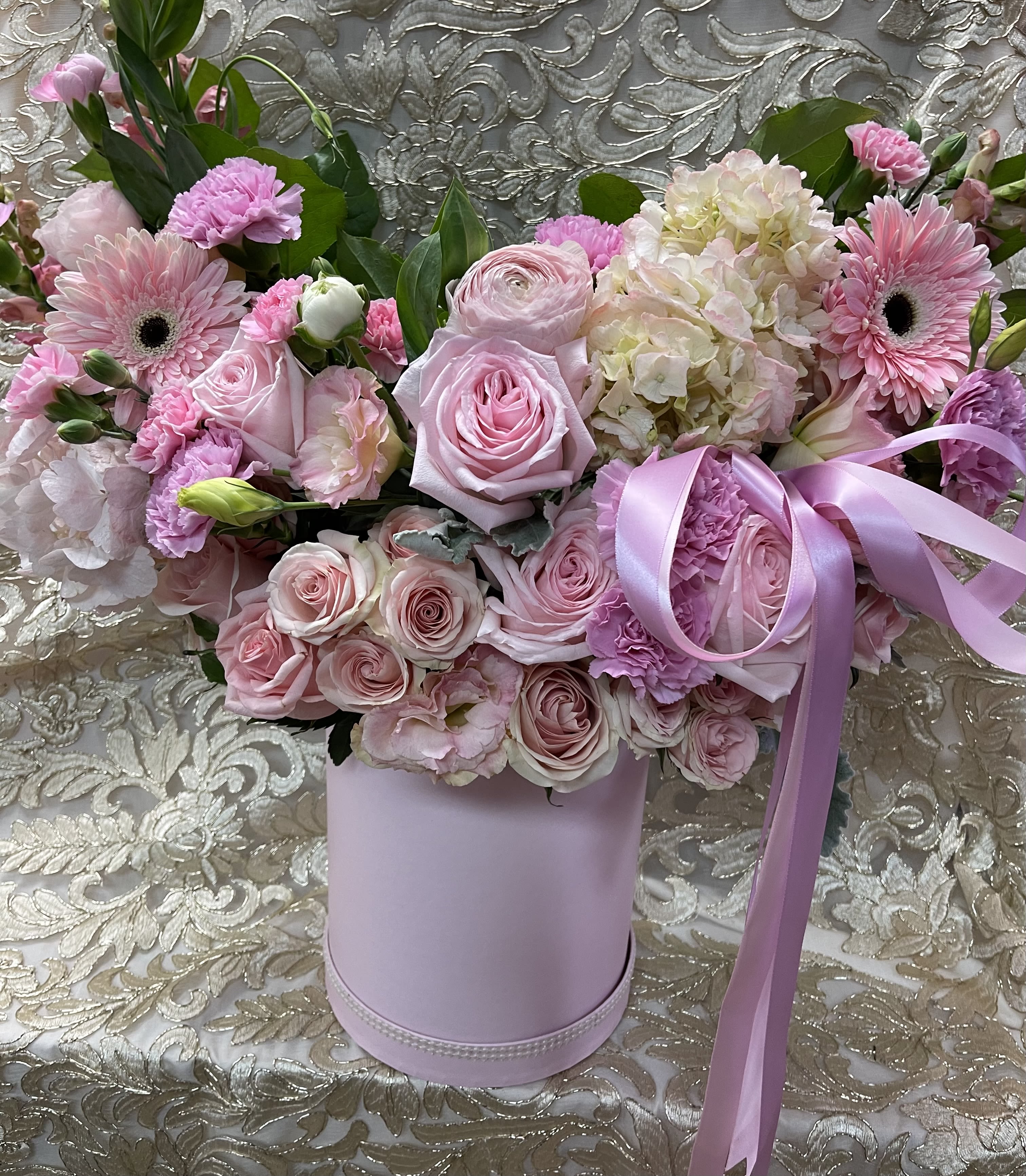 Pink roses and gerbera daisies in a lavender hatbox with ribbon