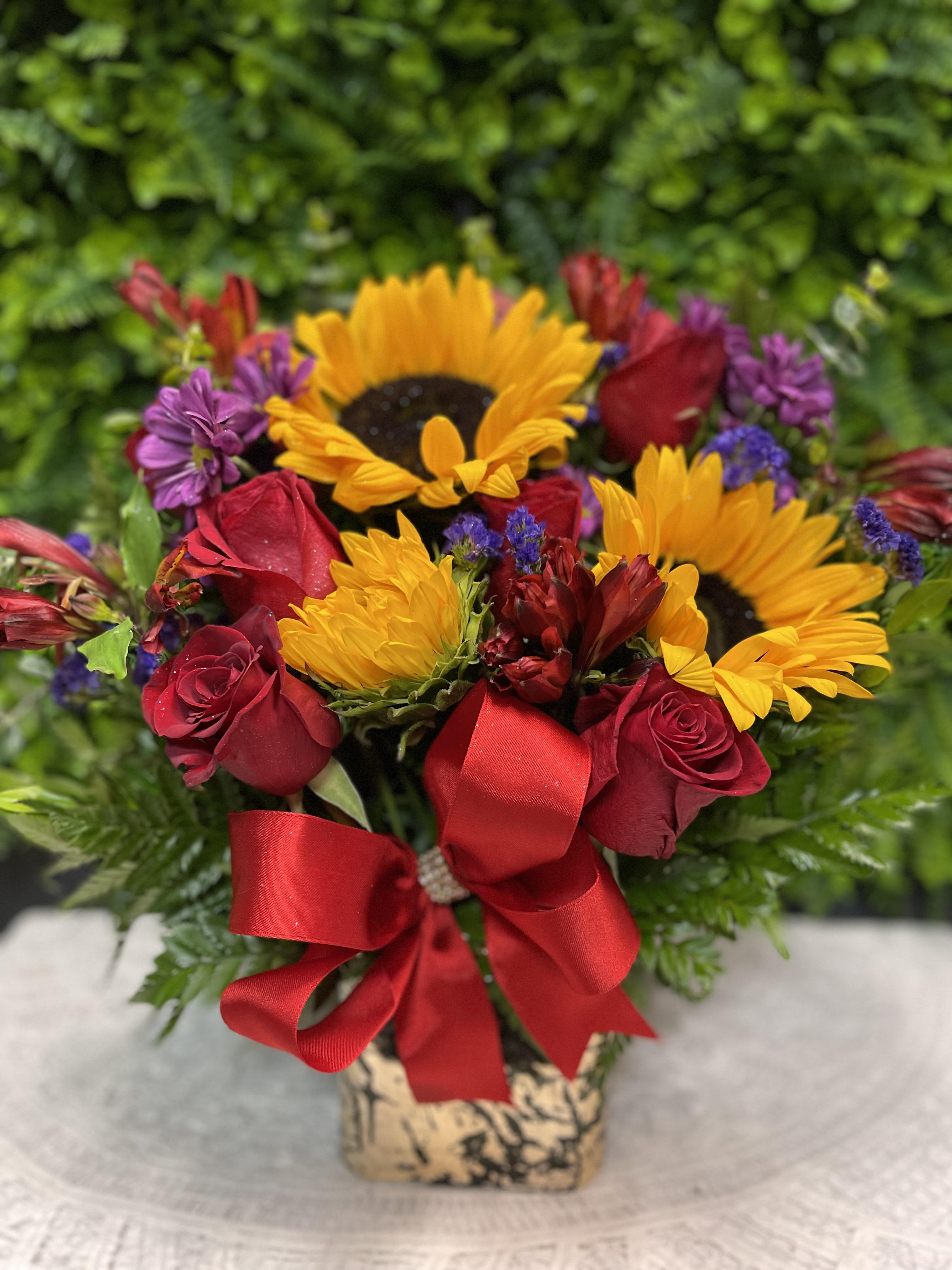 Bouquet of red roses and yellow sunflowers with a red ribbon in a vase