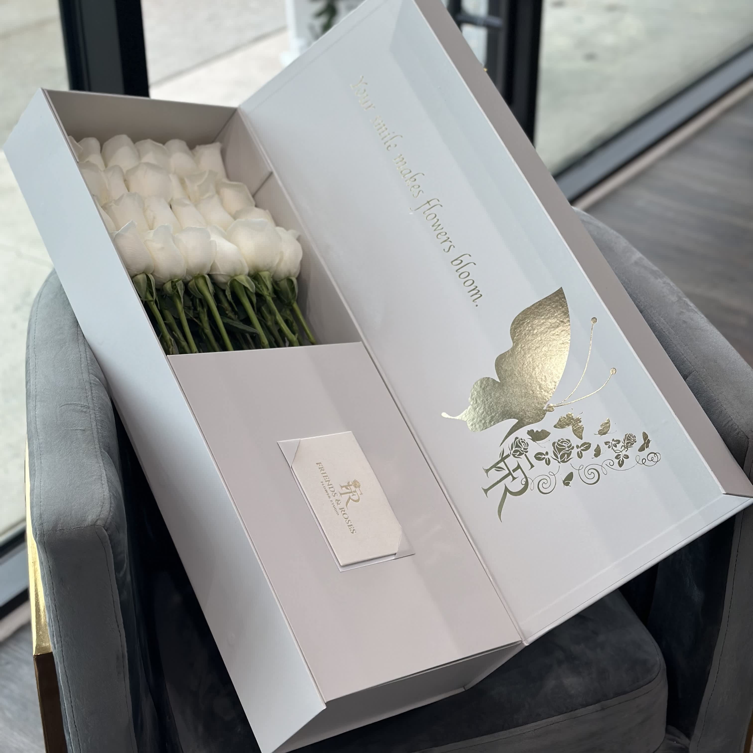 White roses arranged in a presentation box with a gold butterfly design.