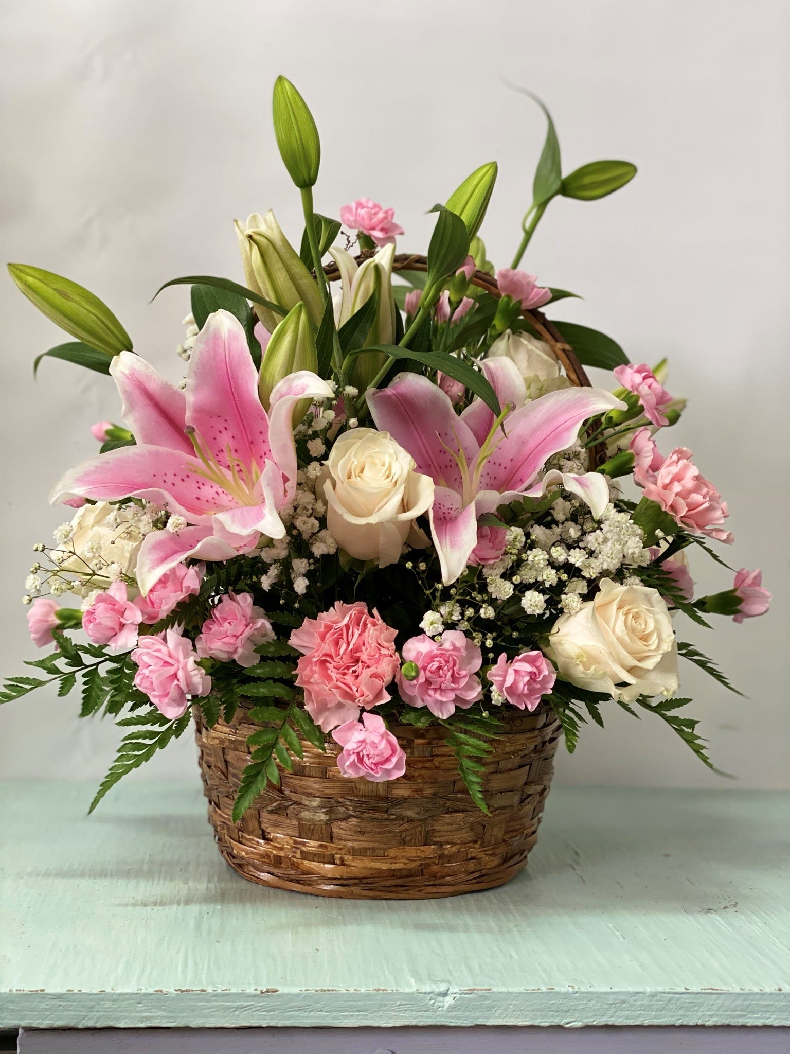 Pink lilies and roses arranged in a wicker basket