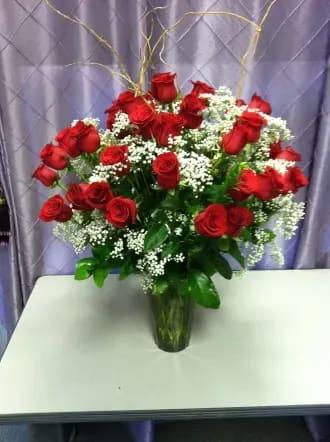 Red roses arranged in a clear glass vase with white filler flowers
