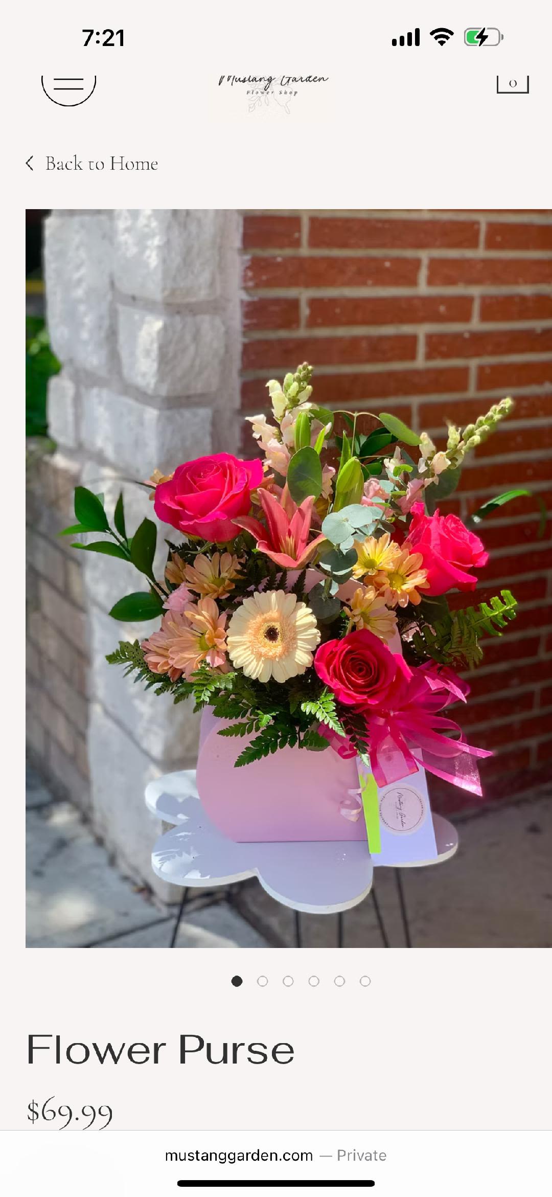 Pink floral arrangement in a purse-shaped container with a ribbon