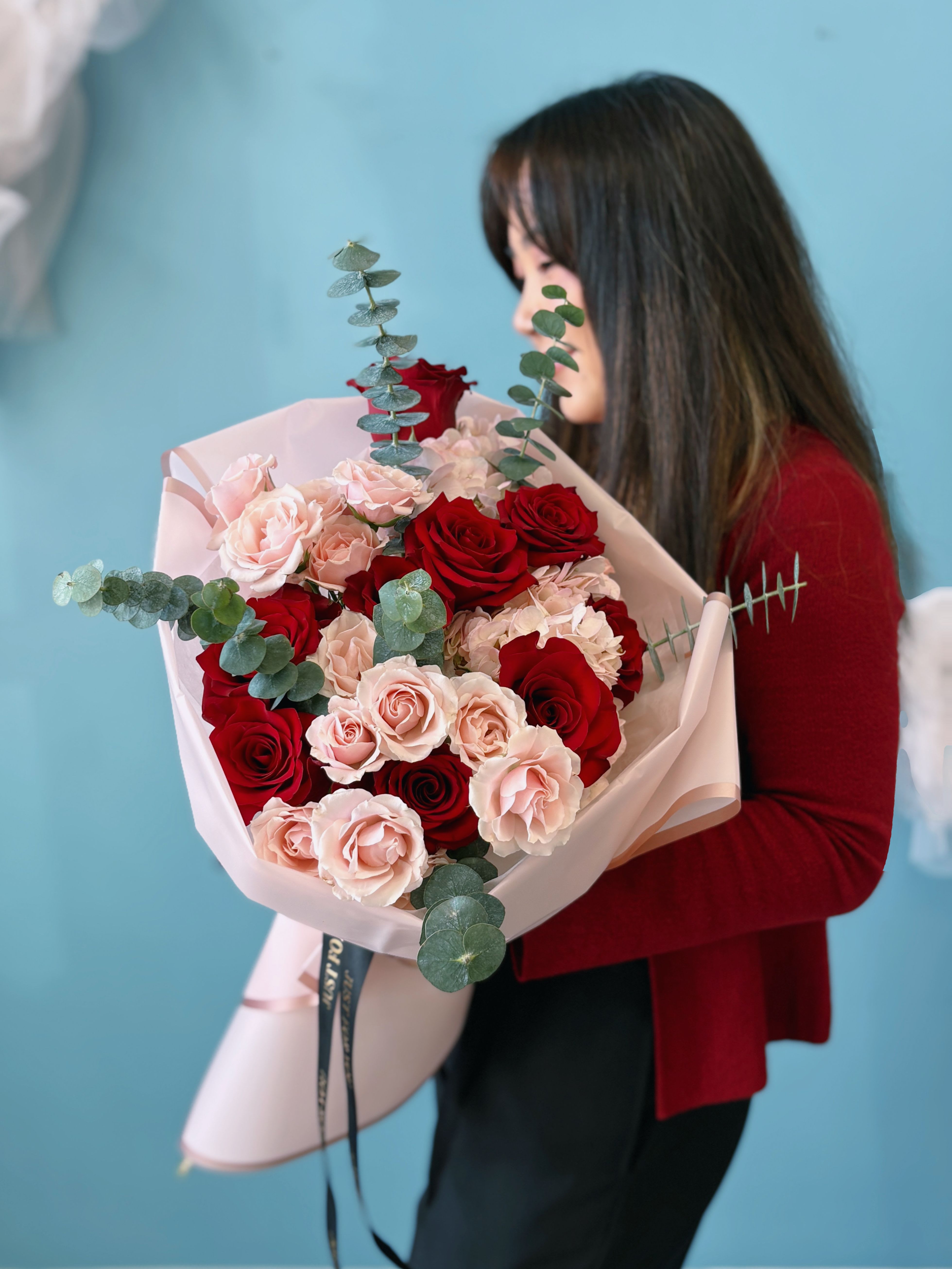Bouquet of red and blush roses wrapped in pale pink paper