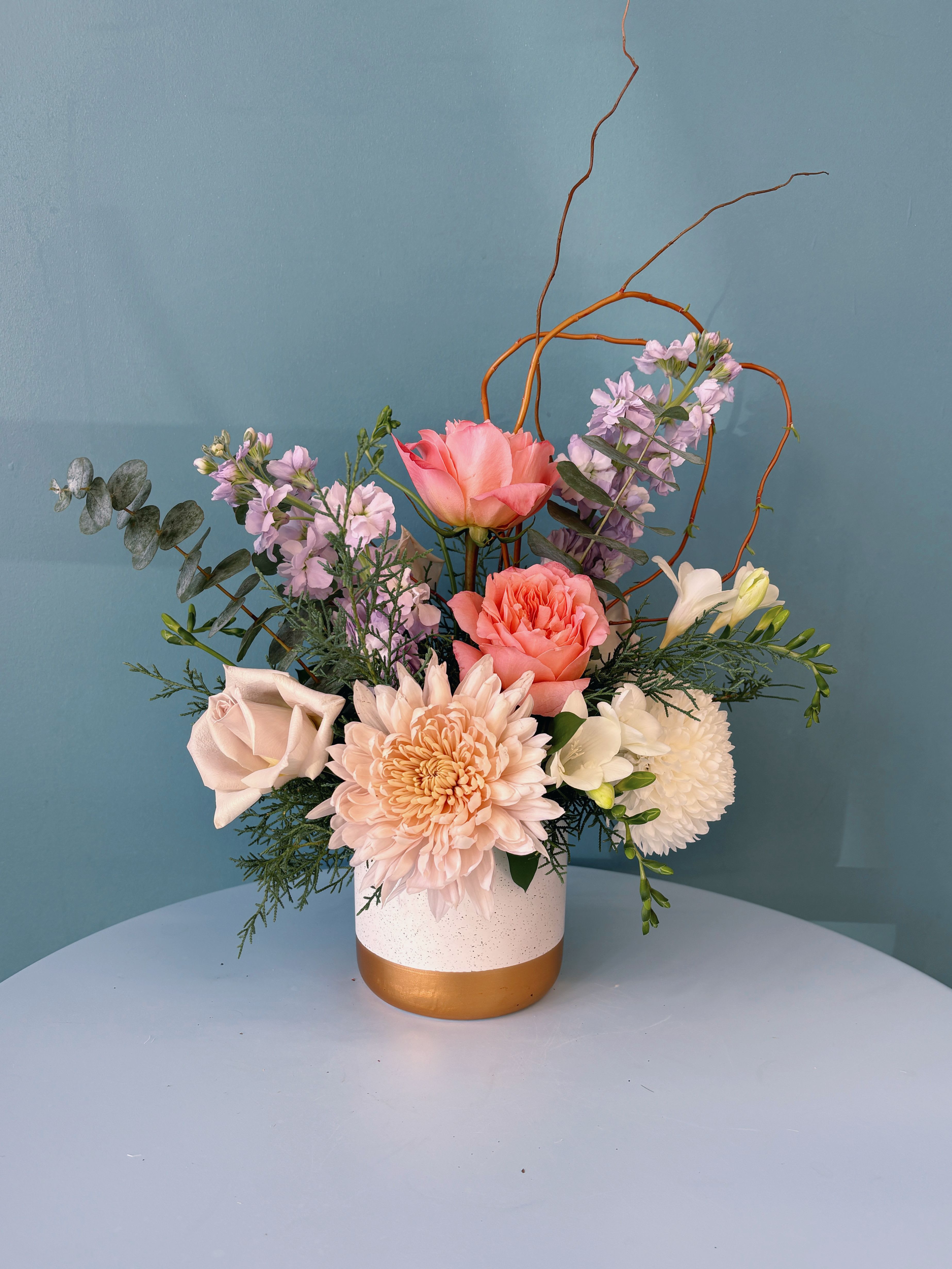 Mixed pastel floral arrangement in a white and gold vase