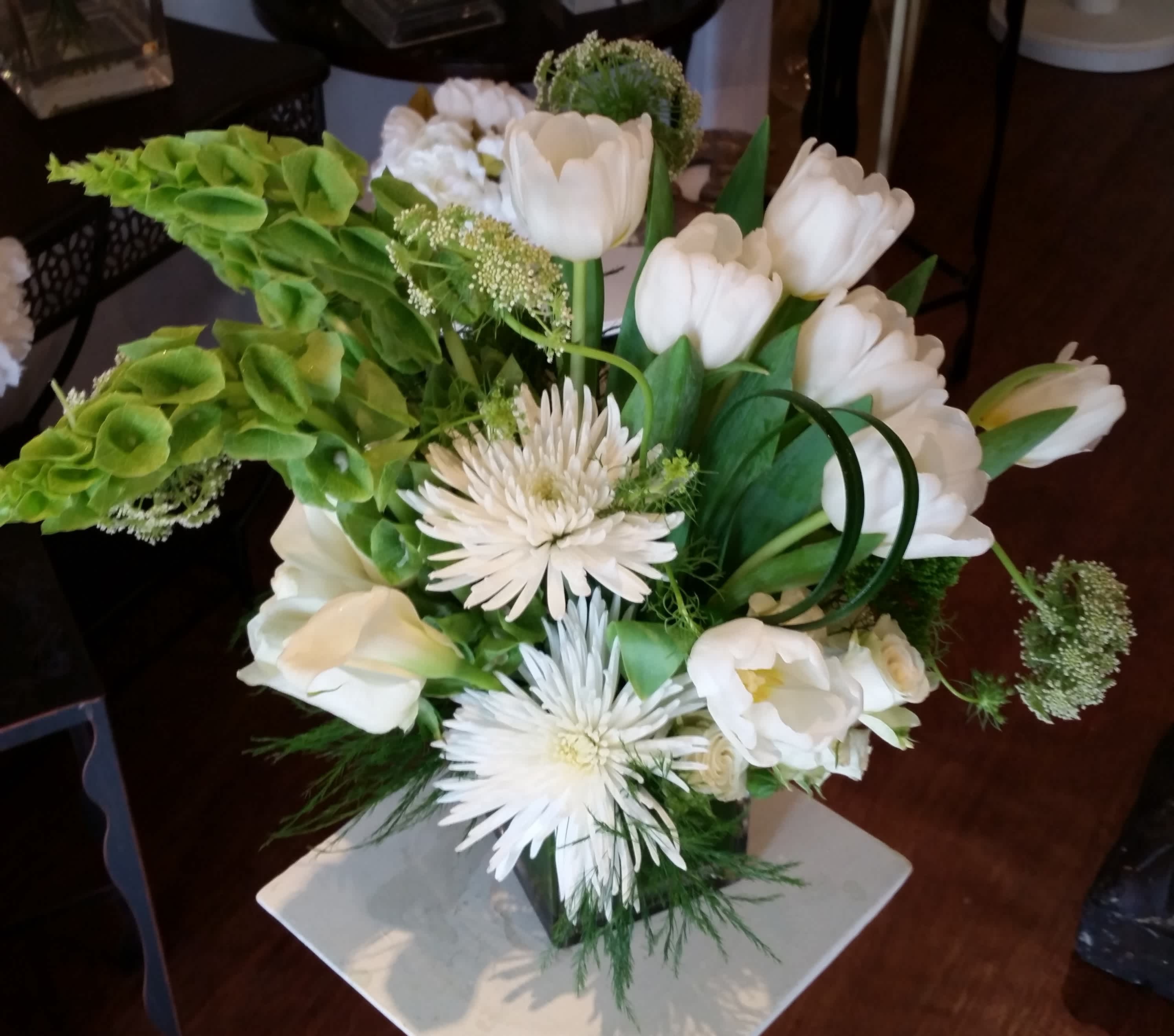 White tulips and spider mums arranged with green blooms in a vase.