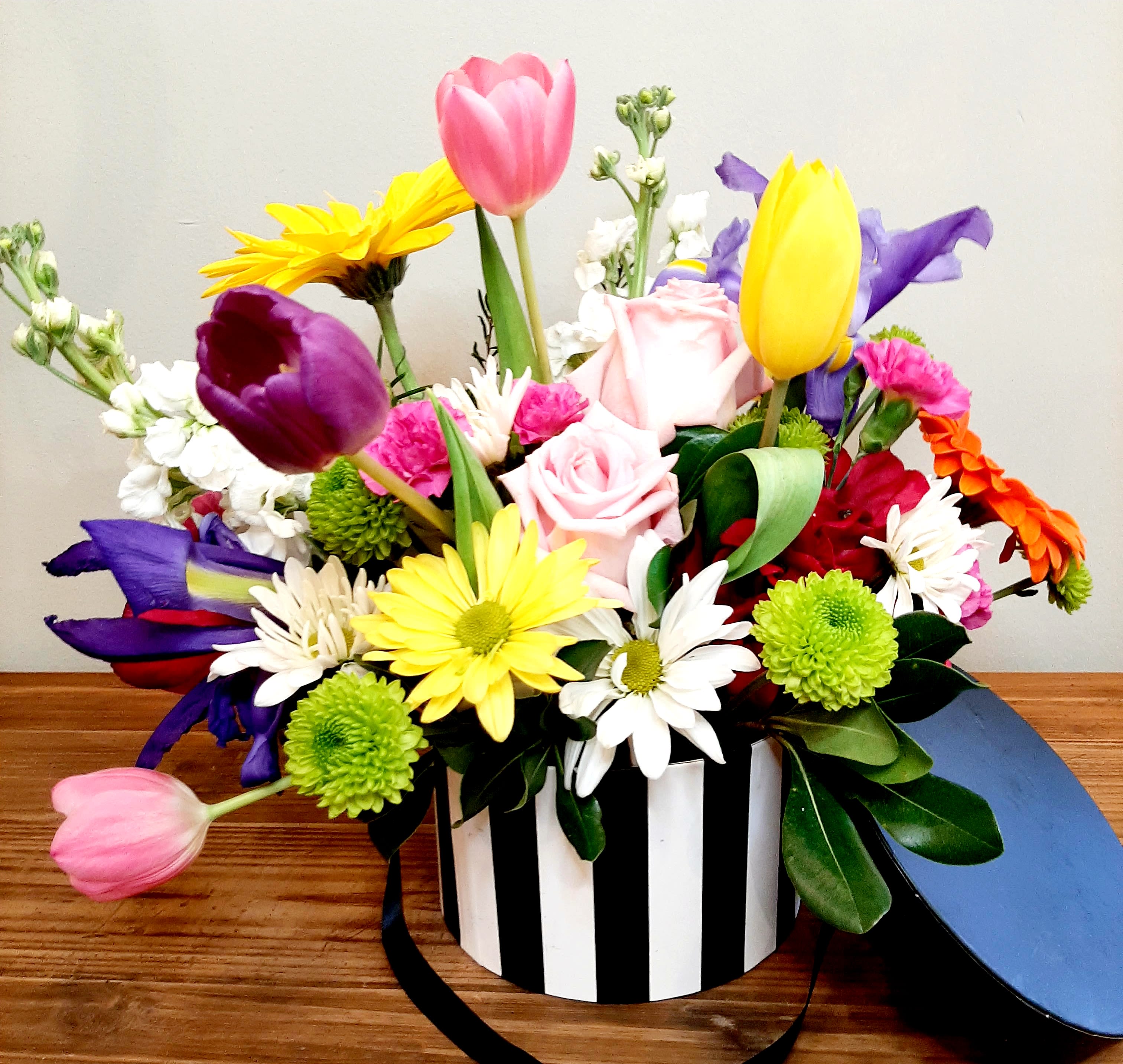 Mixed bouquet in a black-and-white striped box with pink, yellow, purple, and white flowers
