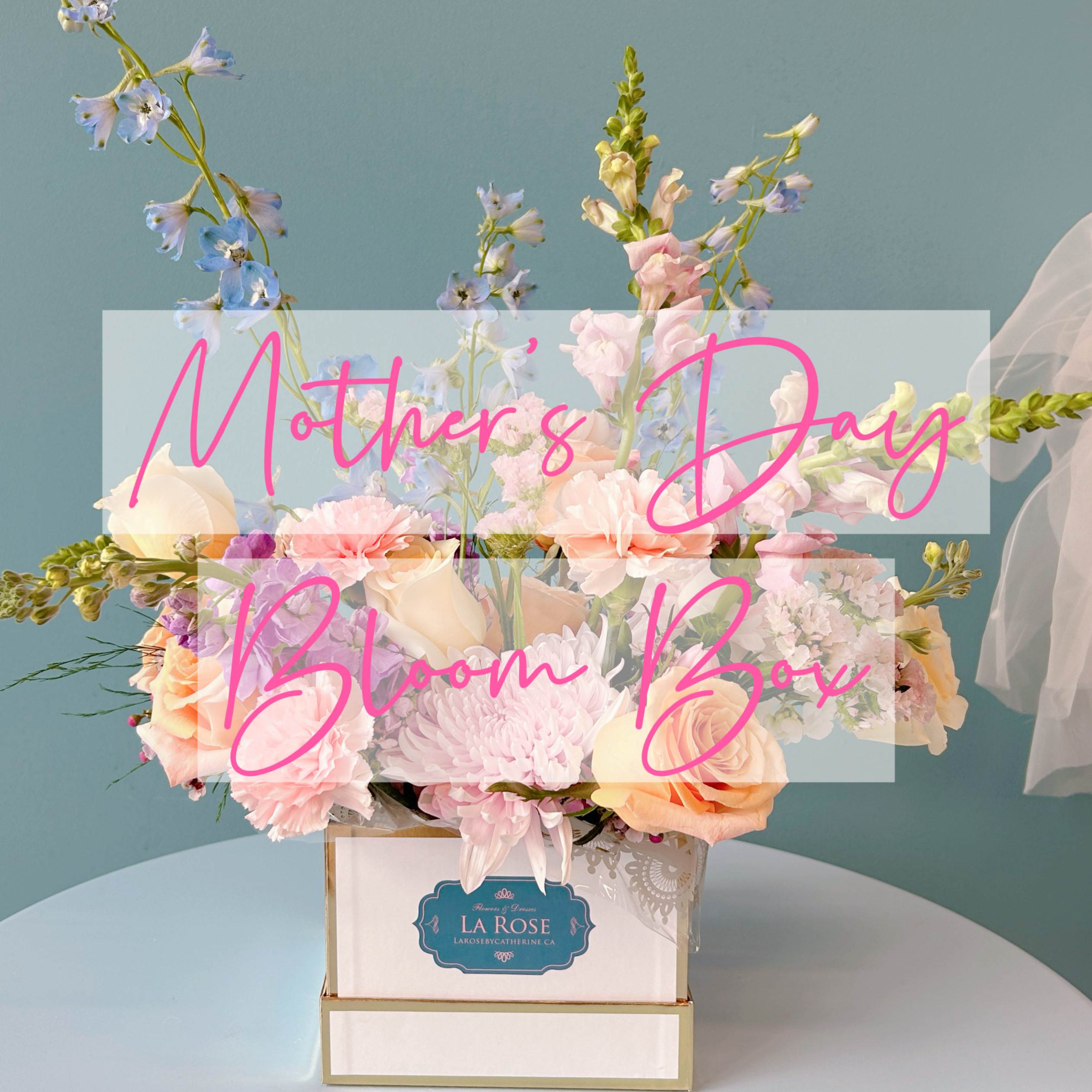 Pastel flower arrangement in a white box with pink lettering.