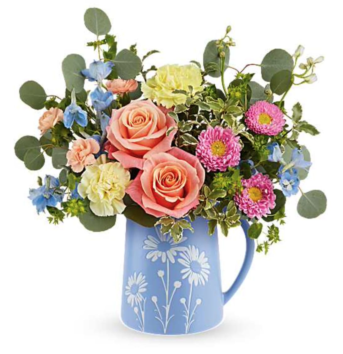 Daisy Dreams Bouquet - Brimming with fresh-picked charm, our Daisy Dreams Bouquet delights with peach roses, yellow carnations, and cheerful blooms arranged in a food-safe blue pitcher adorned with a sweet white daisy design. Teleflora's Daisy Dreams Bouquet features peach roses, yellow carnations, peach miniature carnations, light blue delphinium, pink Matsumoto asters, bupleurum, silver dollar eucalyptus, and pitta negra, presented in the Daisy Dreams Pitcher, a keepsake pitcher with a playful daisy design. Orientation: All-Around  SUBSTITUTION POLICY – Always deliver the freshest flowers! Please note the bouquet pictured reflects our original design.  If the exact flowers or container in this arrangement are not available, our local florists will create a beautiful bouquet with the freshest available flowers