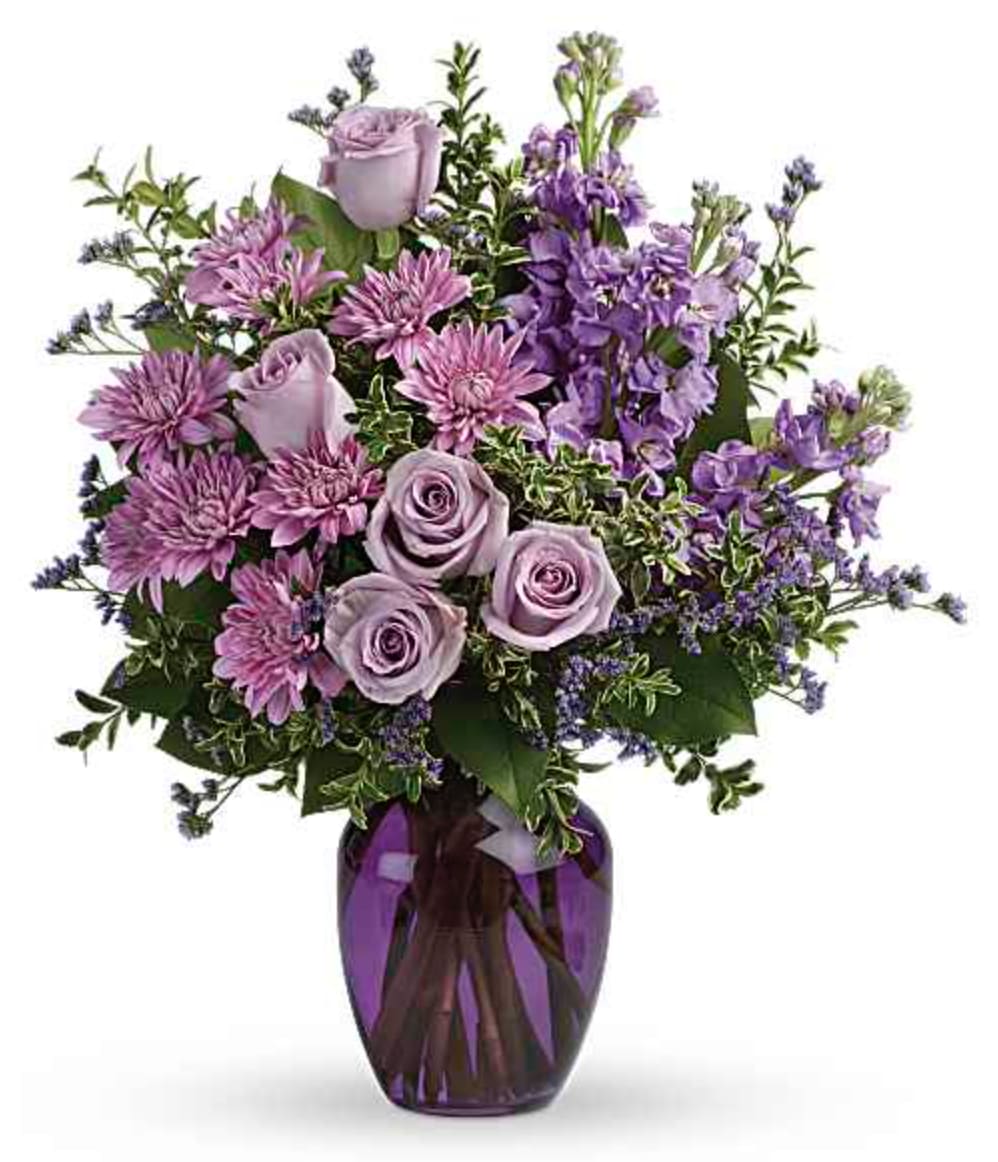 Together at Twilight Bouquet - The perfect pick for the purple lover in your life! This impressive bouquet charms with roses, stock and mums. Presented in a gorgeous glass vase. This dramatic arrangement includes lavender roses, lavender stock, lavender cushion spray chrysanthemums, lavender limonium, oregonia and lemon leaf. Delivered in a purple glass vase. Orientation: All-Around  SUBSTITUTION POLICY – Always deliver the freshest flowers! Please note the bouquet pictured reflects our original design.  If the exact flowers or container in this arrangement are not available, our local florists will create a beautiful bouquet with the freshest available flowers.