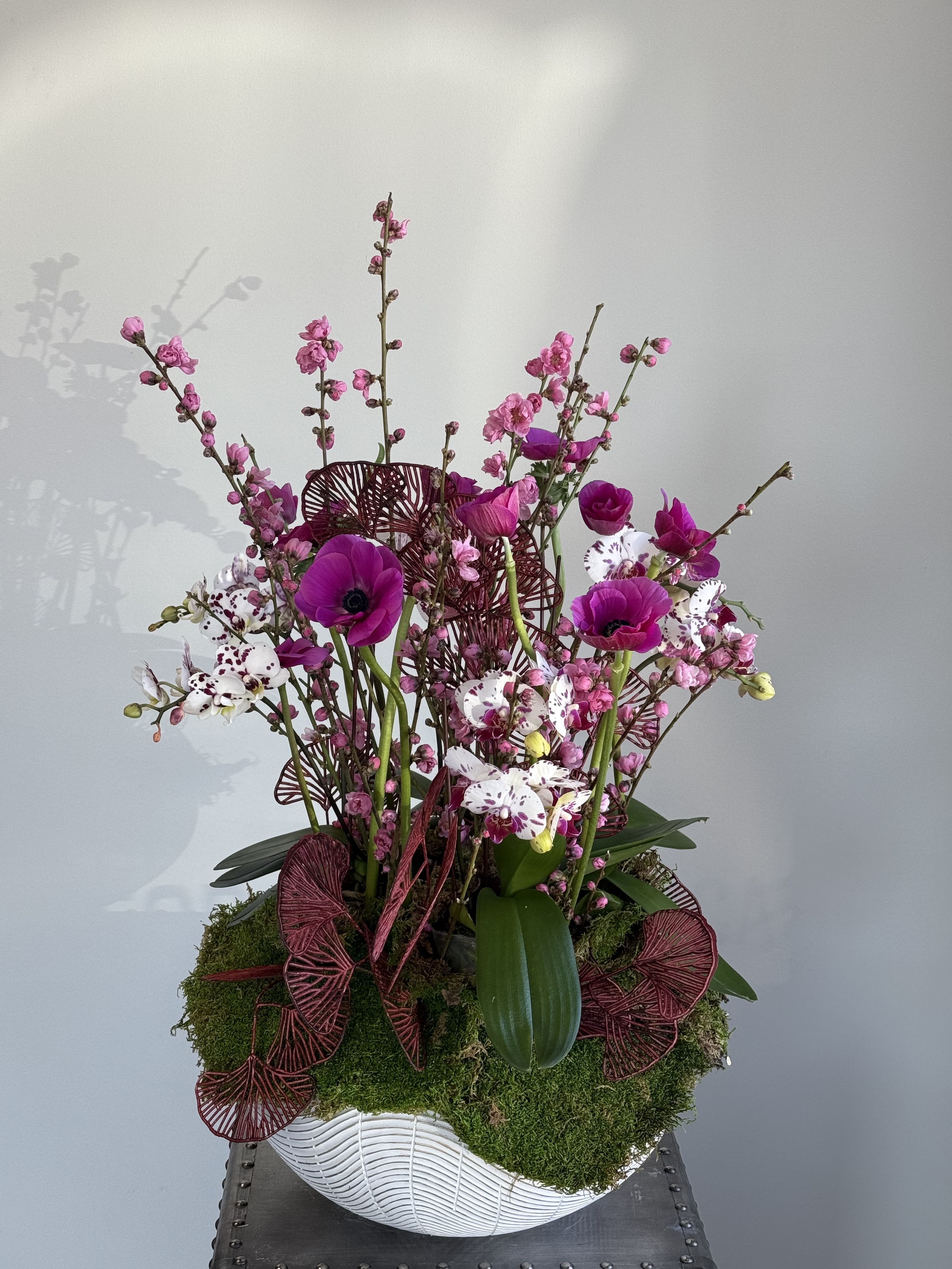 Pink and white orchid arrangement in a white bowl vase