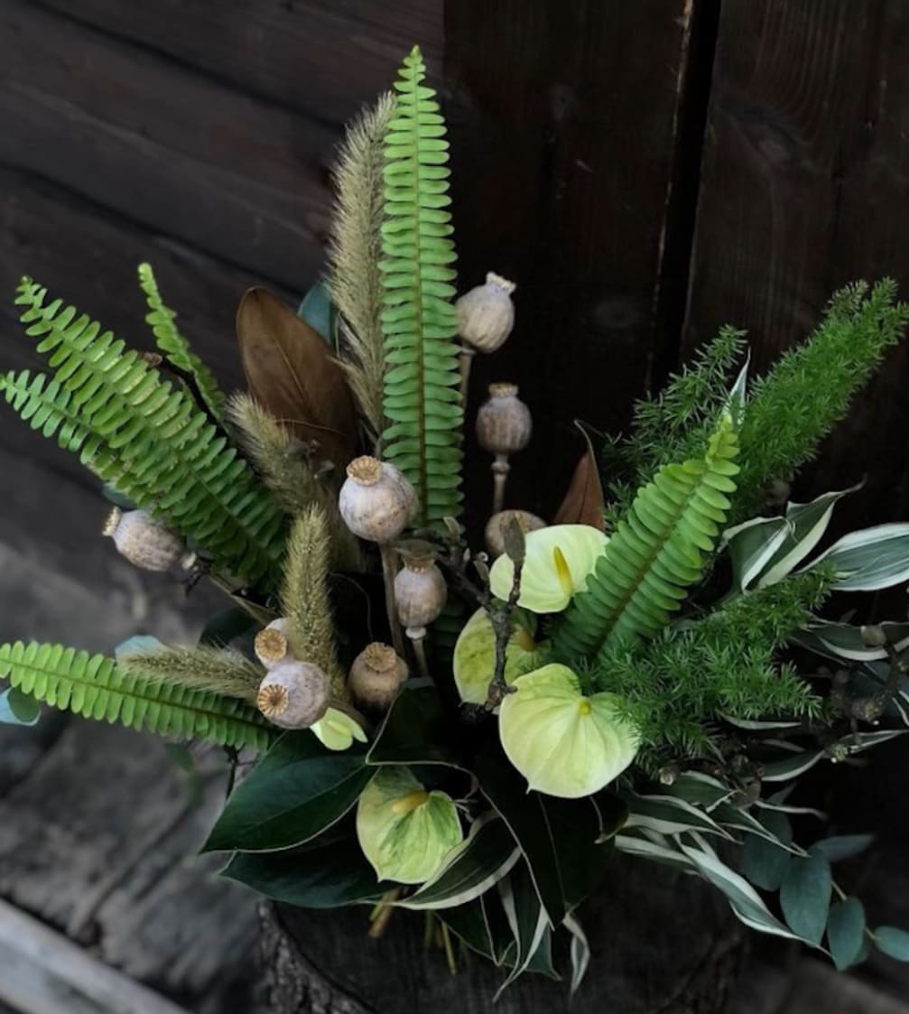 Arrangement with green anthuriums, fern fronds, and seed pods