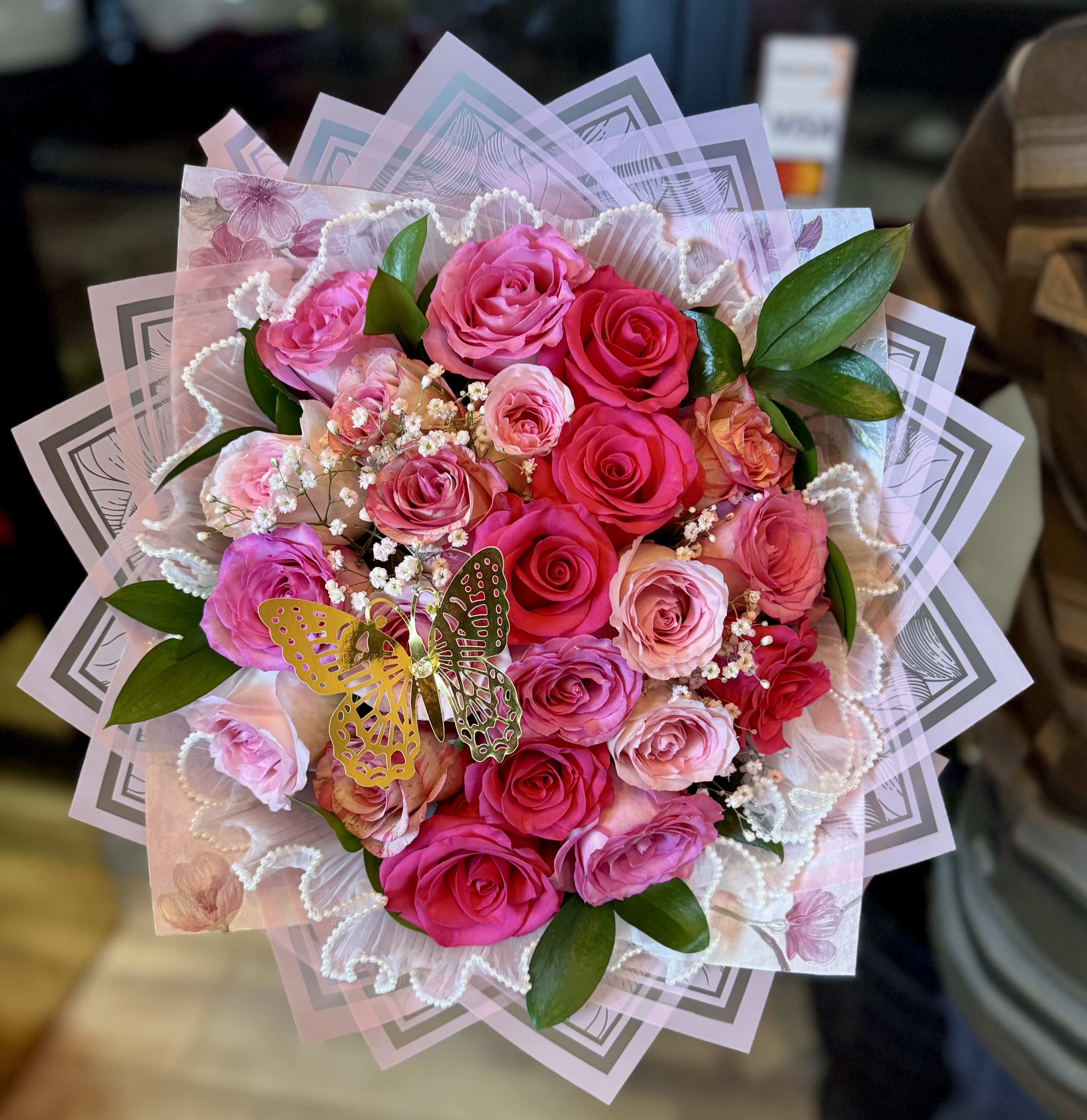 Pink and red rose bouquet with decorative wrapping and a butterfly accent
