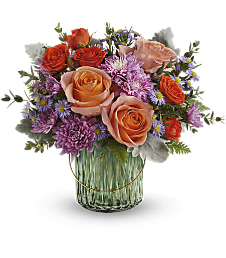 Bouquet of peach and orange roses with purple daisies in a glass vase