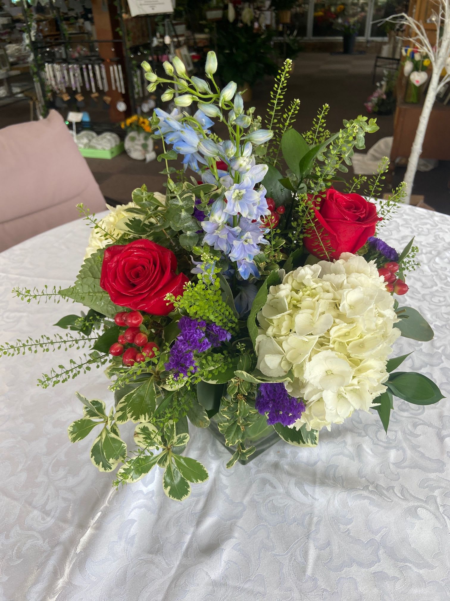  Red Roses and Berries Mother's Day Cube - A beautiful mix of roses, delphinium, hydrangea, statice, and hypericum berries. This arrangement will be sure to make any Mother happy.