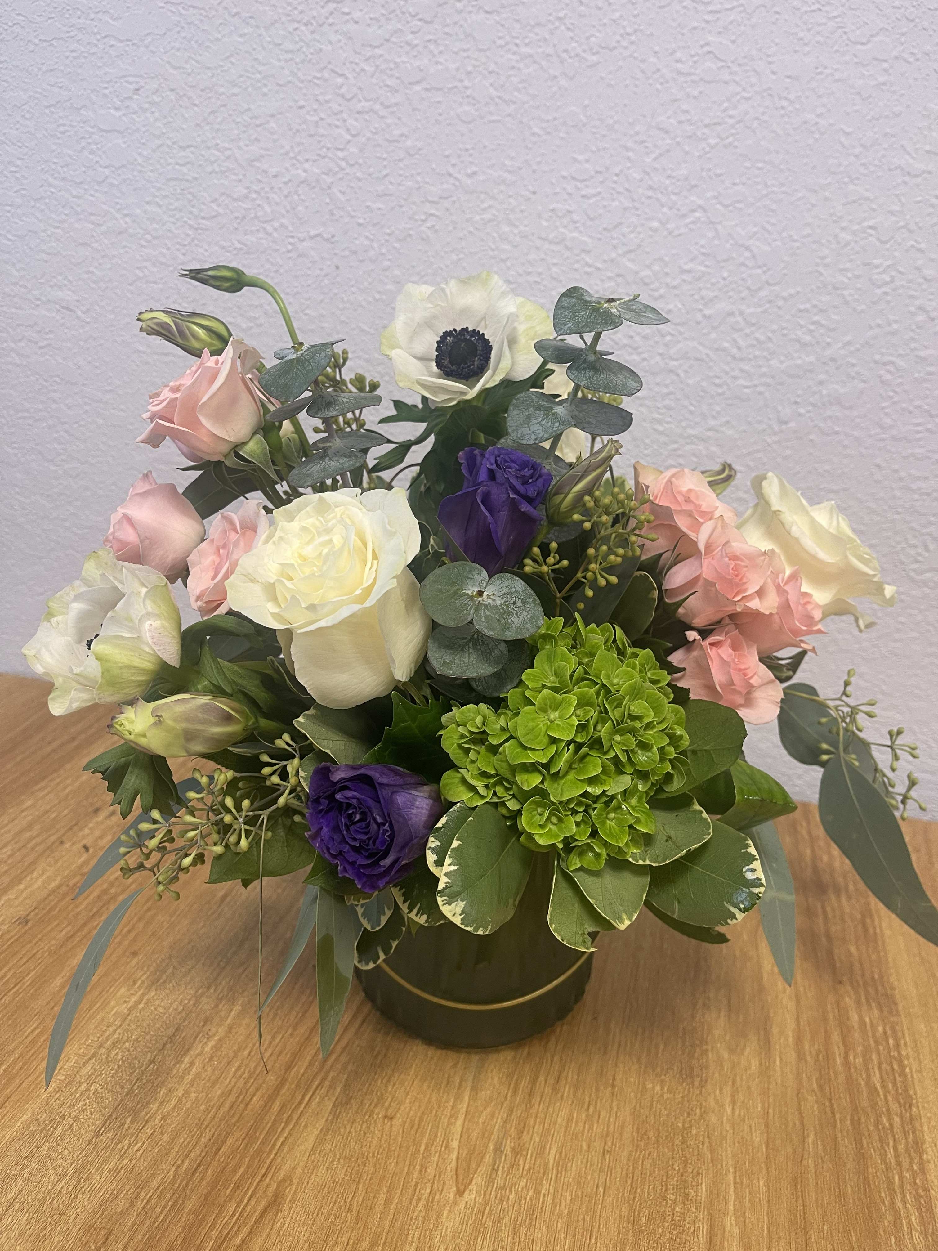 Mixed bouquet of pink, white, purple, and green flowers in a round vase
