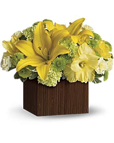 Yellow lilies and white flowers arranged in a square wooden container