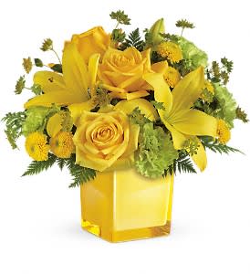 Yellow roses and lilies arranged in a square glass vase