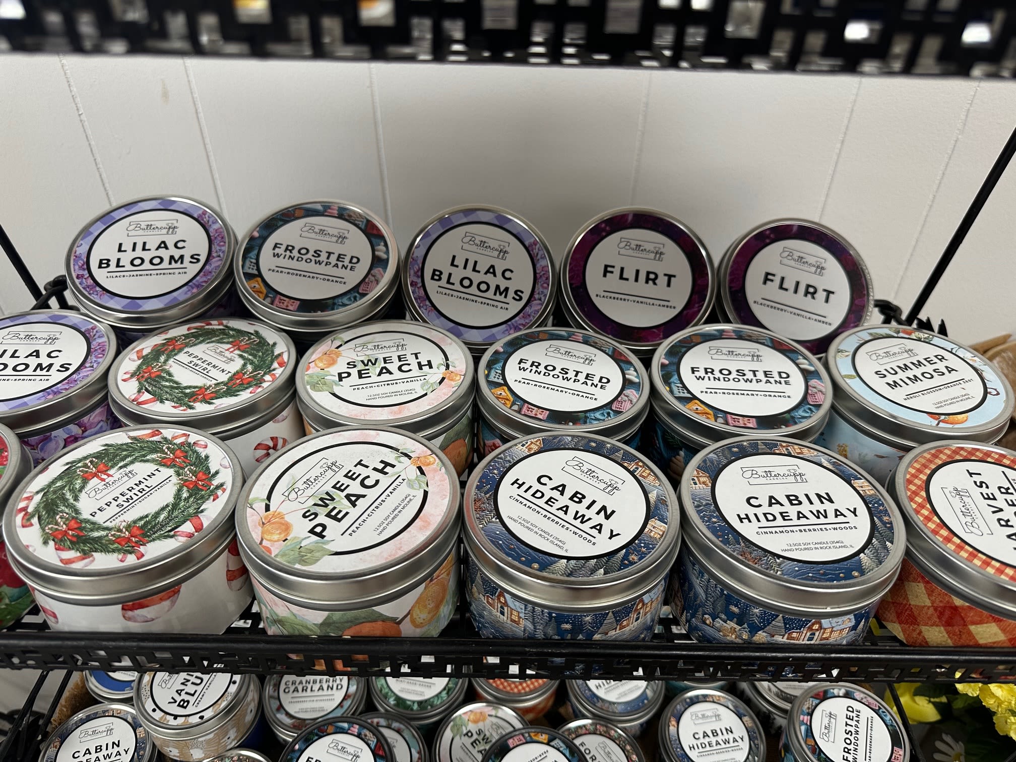 Shelf of scented candles in round metal tins with assorted labels
