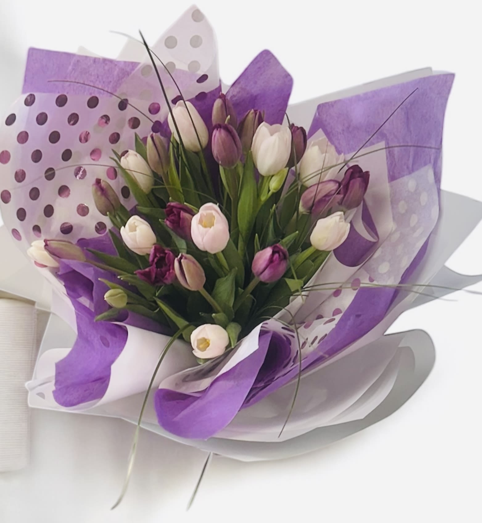 Bouquet of purple and white tulips wrapped in purple paper