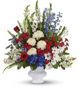 Red roses, white mums, and blue flowers in a white vase