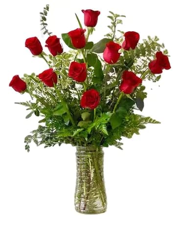 Red roses arranged in a clear glass vase with greenery