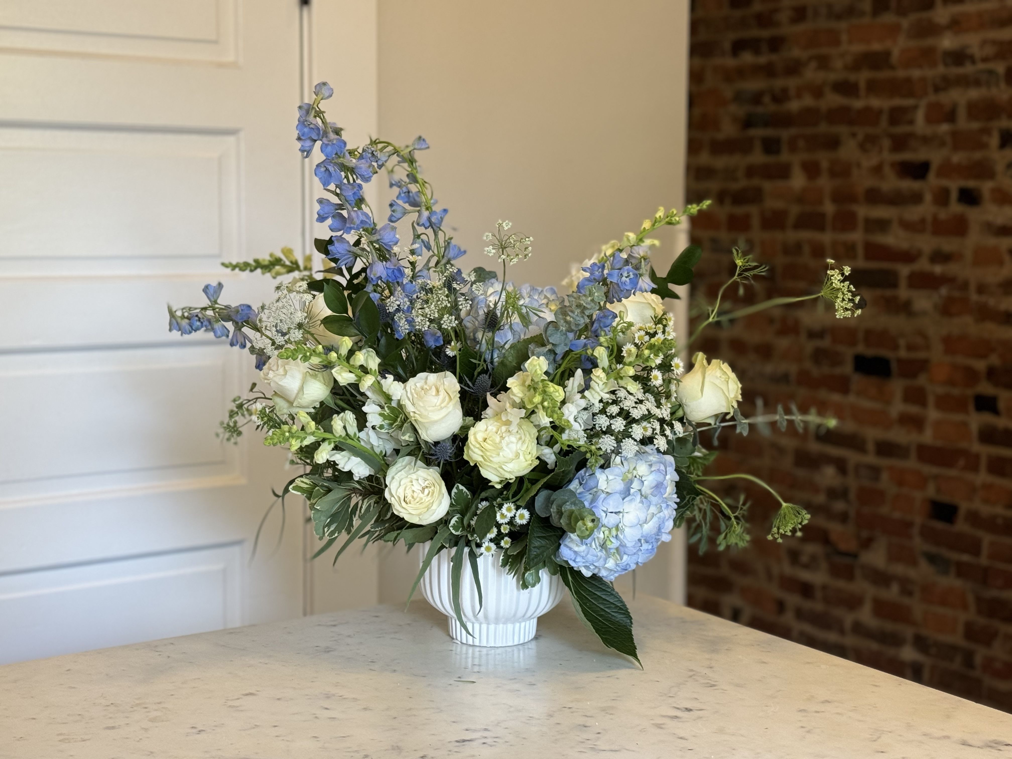 Blue and white floral arrangement in a white vase