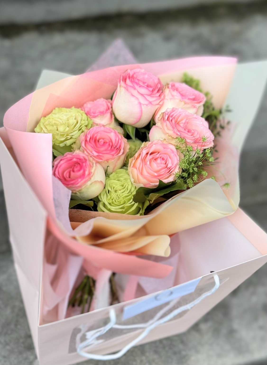 Pink and green rose bouquet wrapped in pastel paper